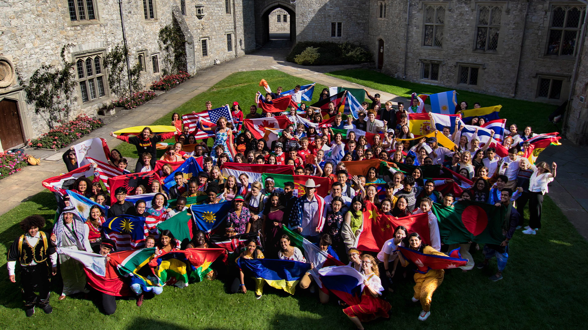 Een groep internationale leerlingen van het Atlantic College in Wales met vlaggen van hun landen. Foto: UWC