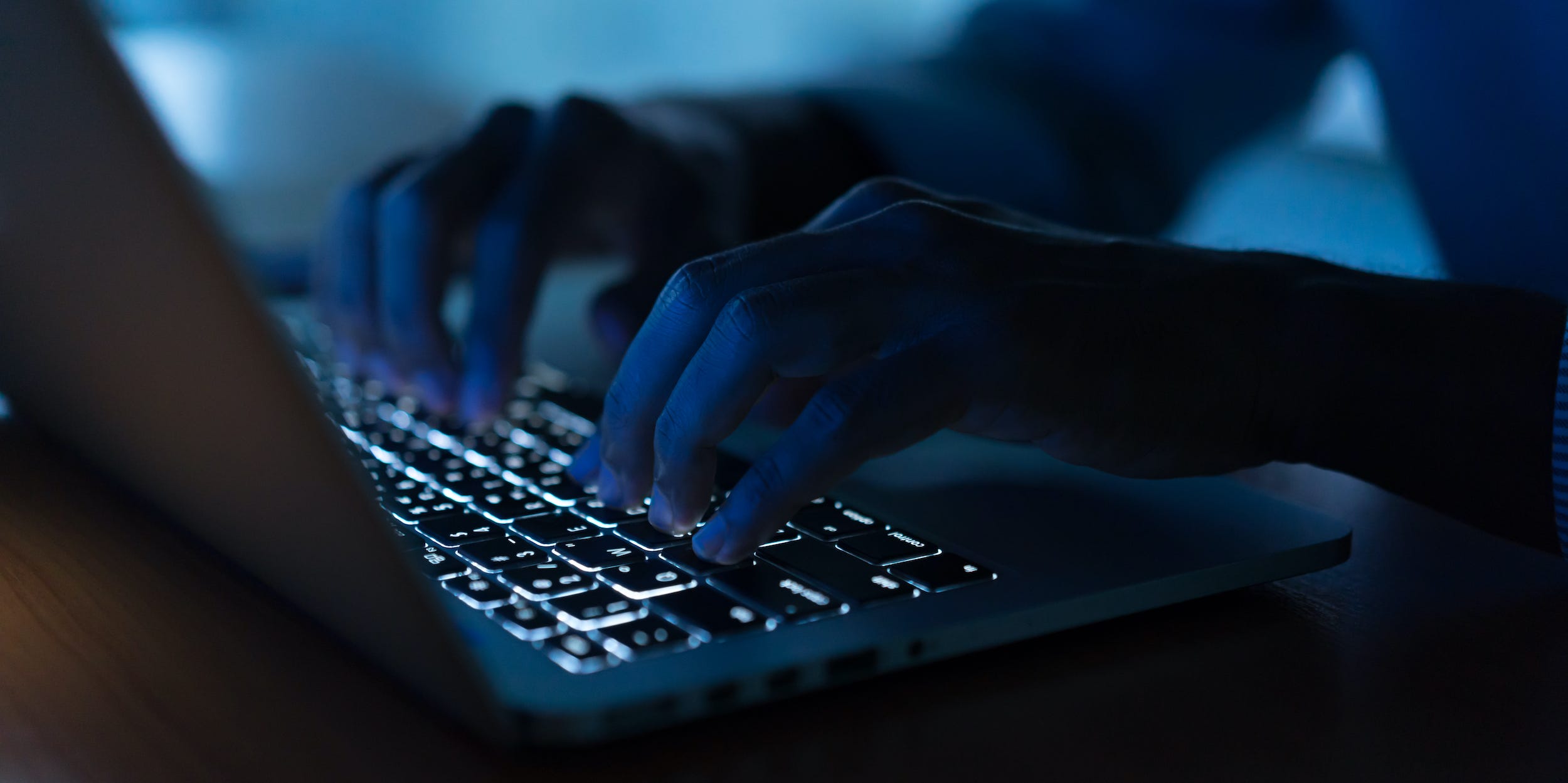 hands typing on laptop mac keyboard dark