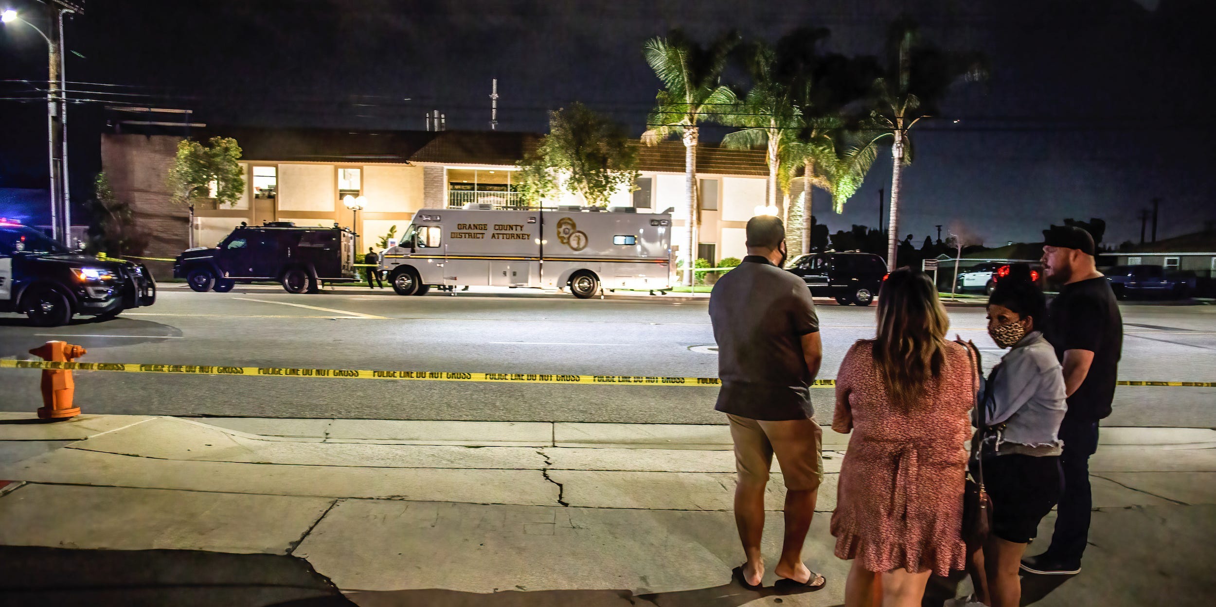 Locals stand and wait for updates across the street from where the shooting occurred. On Wednesday evening, four people, including a child, were killed in an office building in Orange, California. The suspect and another person were injured as well. This is the third major shooting in the United States in the last three weeks.