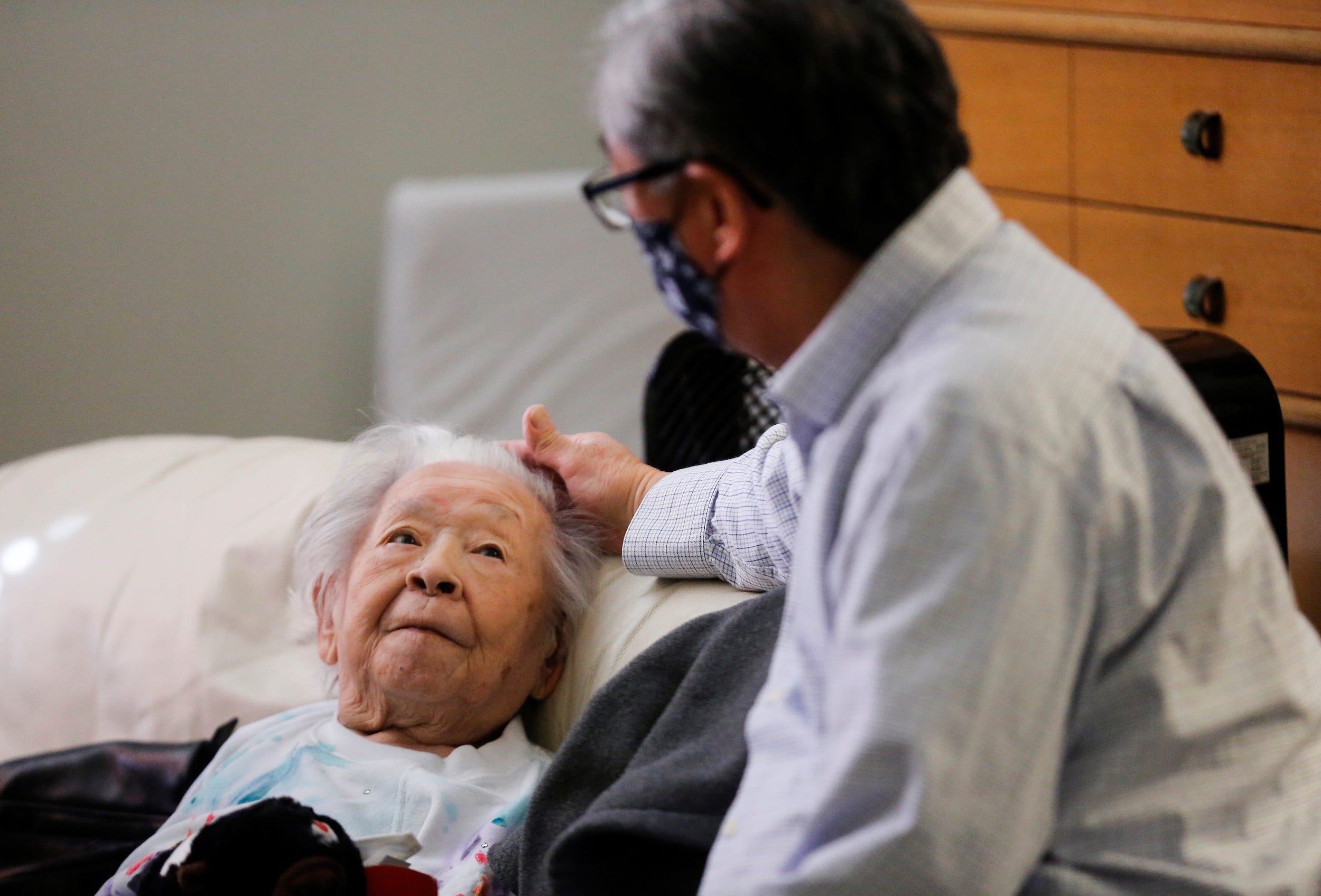 Uomoto, 98, looks up at her son Uomoto as they visit in person for the first time in a year at Nikkei Manor, an assisted living facility in Seattle