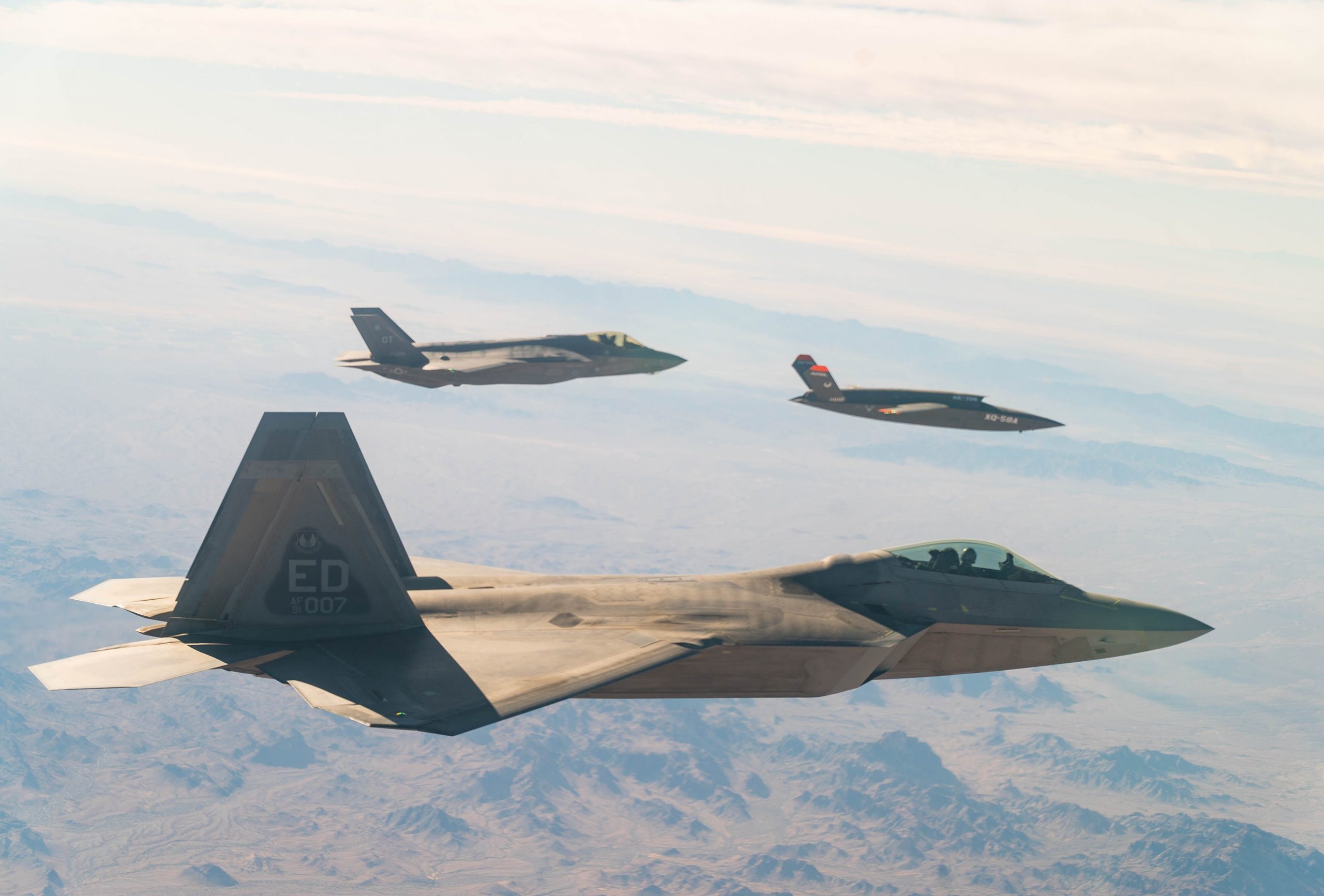 A U.S. Air Force F-22 Raptor and F-35A Lightning II fly in formation with the XQ-58A Valkyrie low-cost unmanned aerial vehicle over the U.S. Army Yuma Proving Ground testing range, Ariz., during a series of tests Dec. 9, 2020