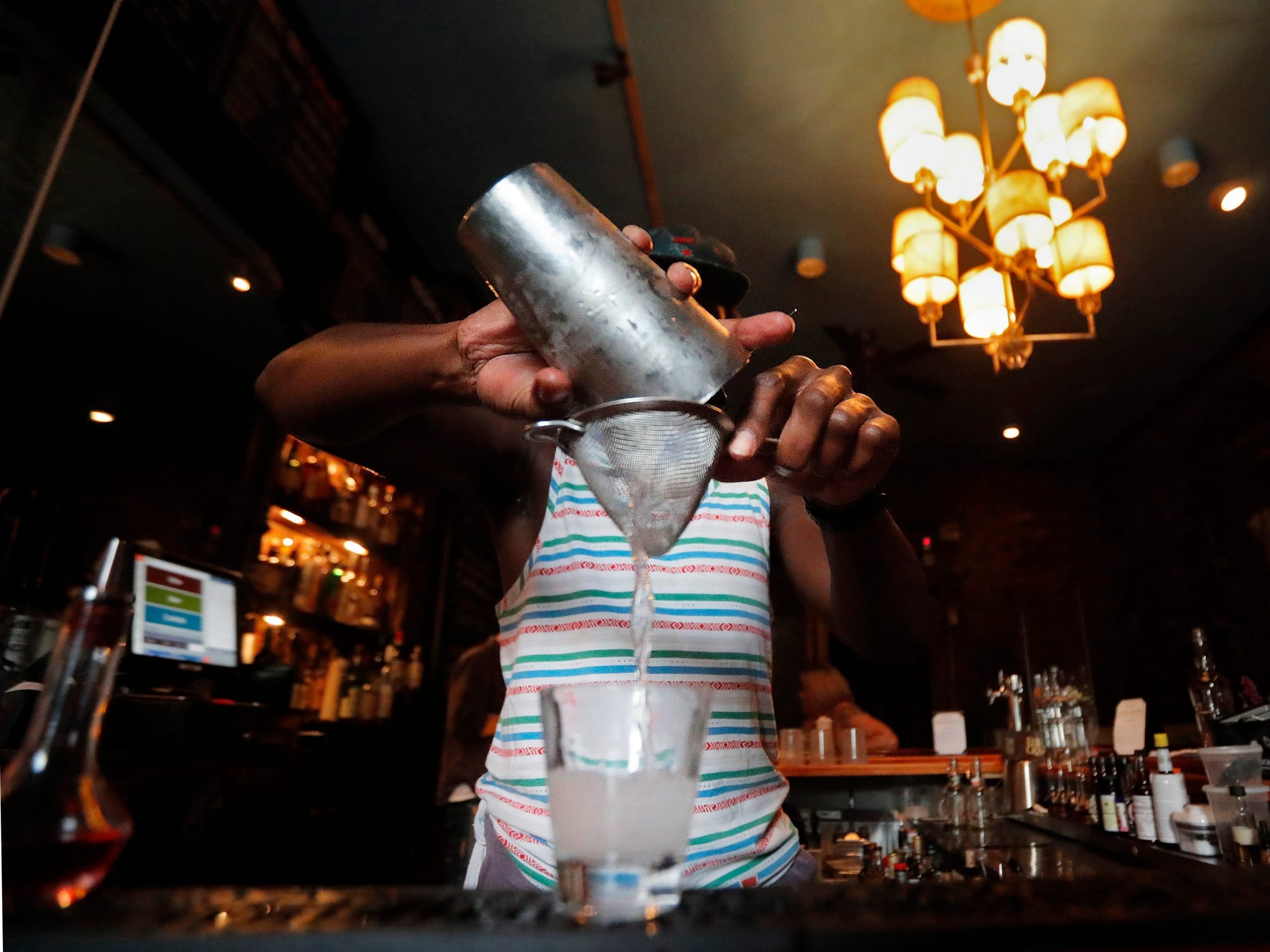 FILE - In this Thursday, July 9, 2020 file photo, a bartender makes a cocktail in New Orleans. A report released Wednesday, July 15, 2020, finds if you decide to have an alcoholic drink, limiting yourself to one a day is best - whether you’re a man or woman. (AP Photo/Gerald Herbert)