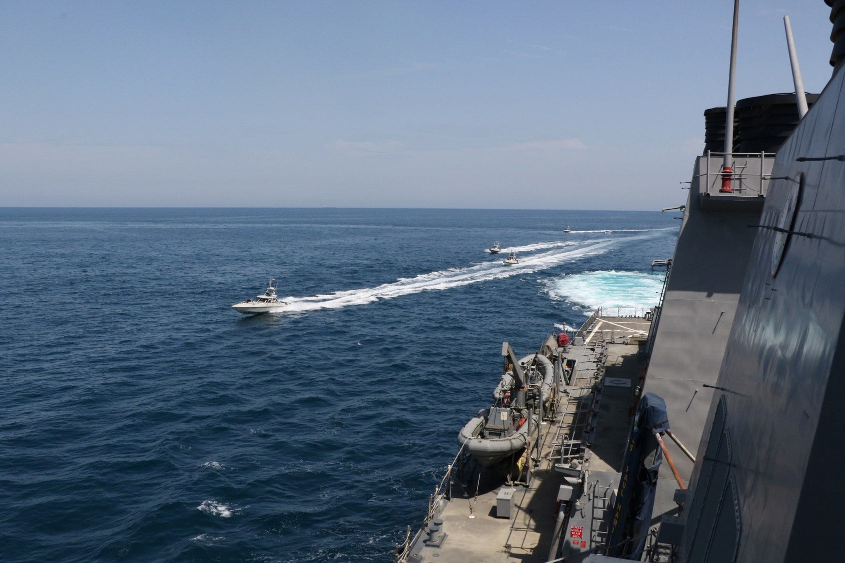 FILE PHOTO: Four Iranian Islamic Revolutionary Guard Corps Navy (IRGCN) vessels, some of several to maneuver in what the U.S. Navy says are "unsafe and unprofessional actions against U.S. Military ships by crossing the ships’ bows and sterns at close range" is seen next to the guided-missile destroyer USS Paul Hamilton in the Gulf April 15, 2020. U.S. Navy/Handout via REUTERS