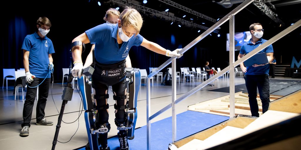 Studenten van de TU Delft demonstreren een exoskelet.