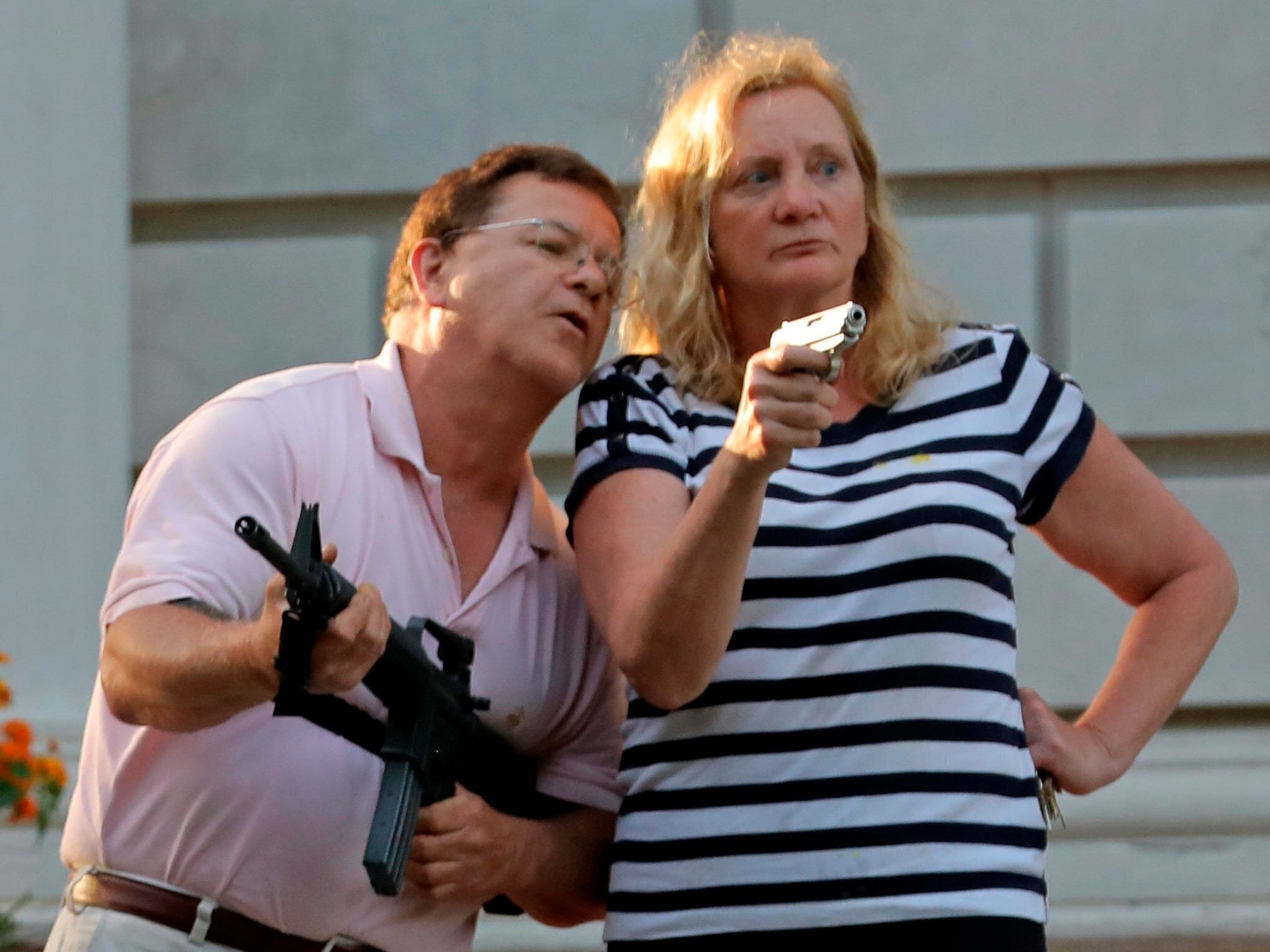 FILE - In this June 28, 2020 file photo, armed homeowners Mark and Patricia McCloskey, standing in front their house along Portland Place confront protesters marching to St. Louis Mayor Lyda Krewson's house in the Central West End of St. Louis. Authorities executed a search warrant Friday evening, July 10, 2020, at the St. Louis mansion owned by the McCloskey's, a white couple whose armed defense of their home during a racial injustice protest last month made national headlines. said. Joel Schwartz, who is now representing the couple, confirmed on Saturday that a search warrant was served, and that the gun Mark McCloskey was seen holding during last month's protest was seized. (Laurie Skrivan/St. Louis Post-Dispatch via AP)