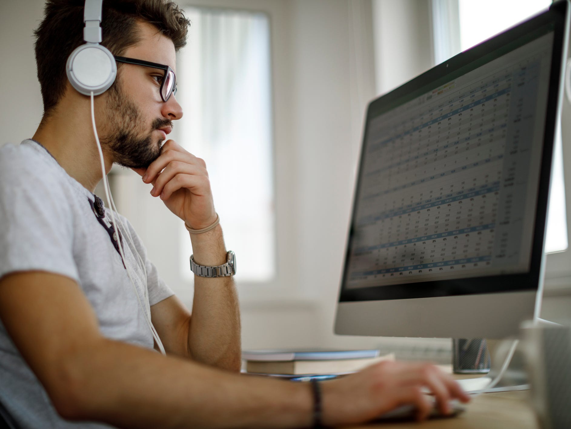 Person in headphones working on spreadsheet on desktop Mac.