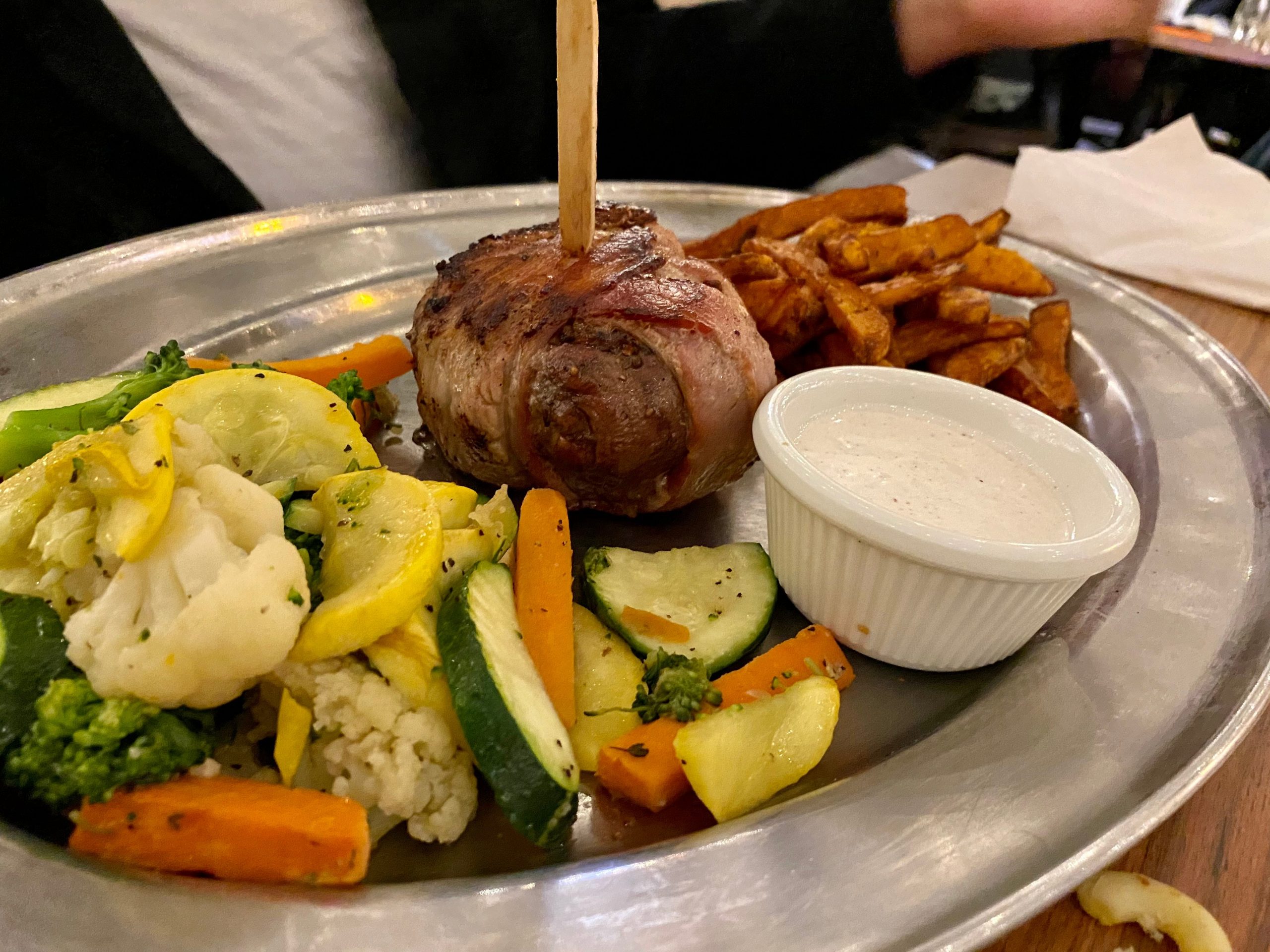 Bacon-wrapped filet mignon with mixed vegetables and sweet potato fries