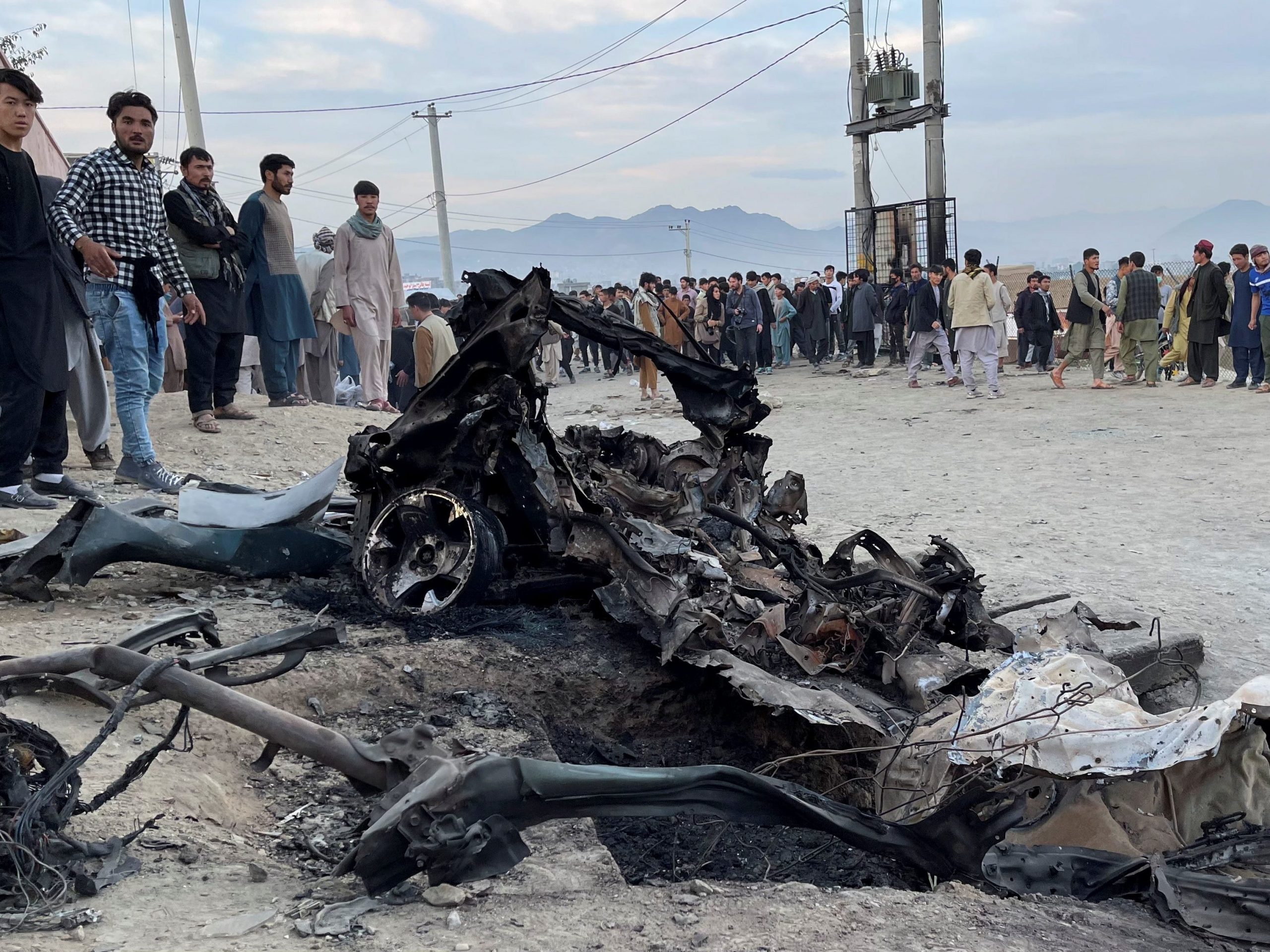 People stand at site of car explosion in. Kabul, Afghanistan