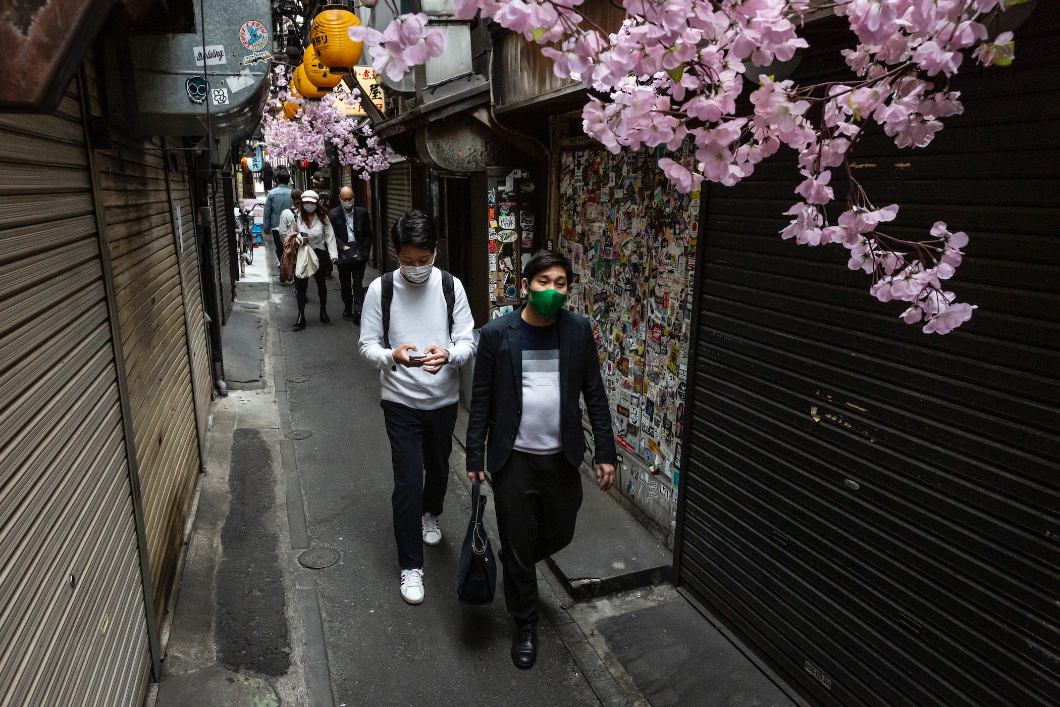 People wearing face masks walk past closed bars that have temporarily closed due to the current state of emergency on April 25, 2021 in Tokyo, Japan.