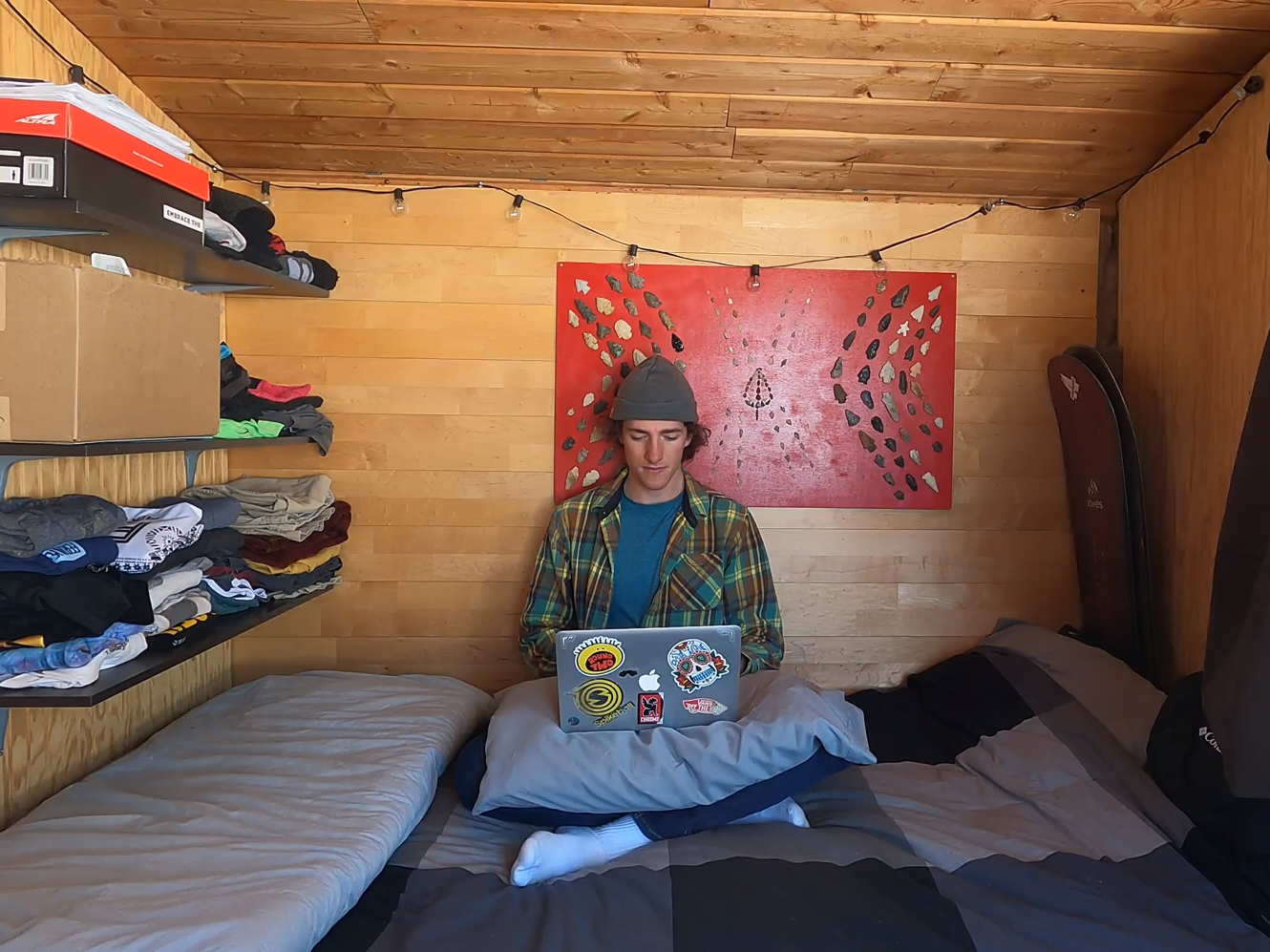 Keenan Laurence on computer on bed in tiny home