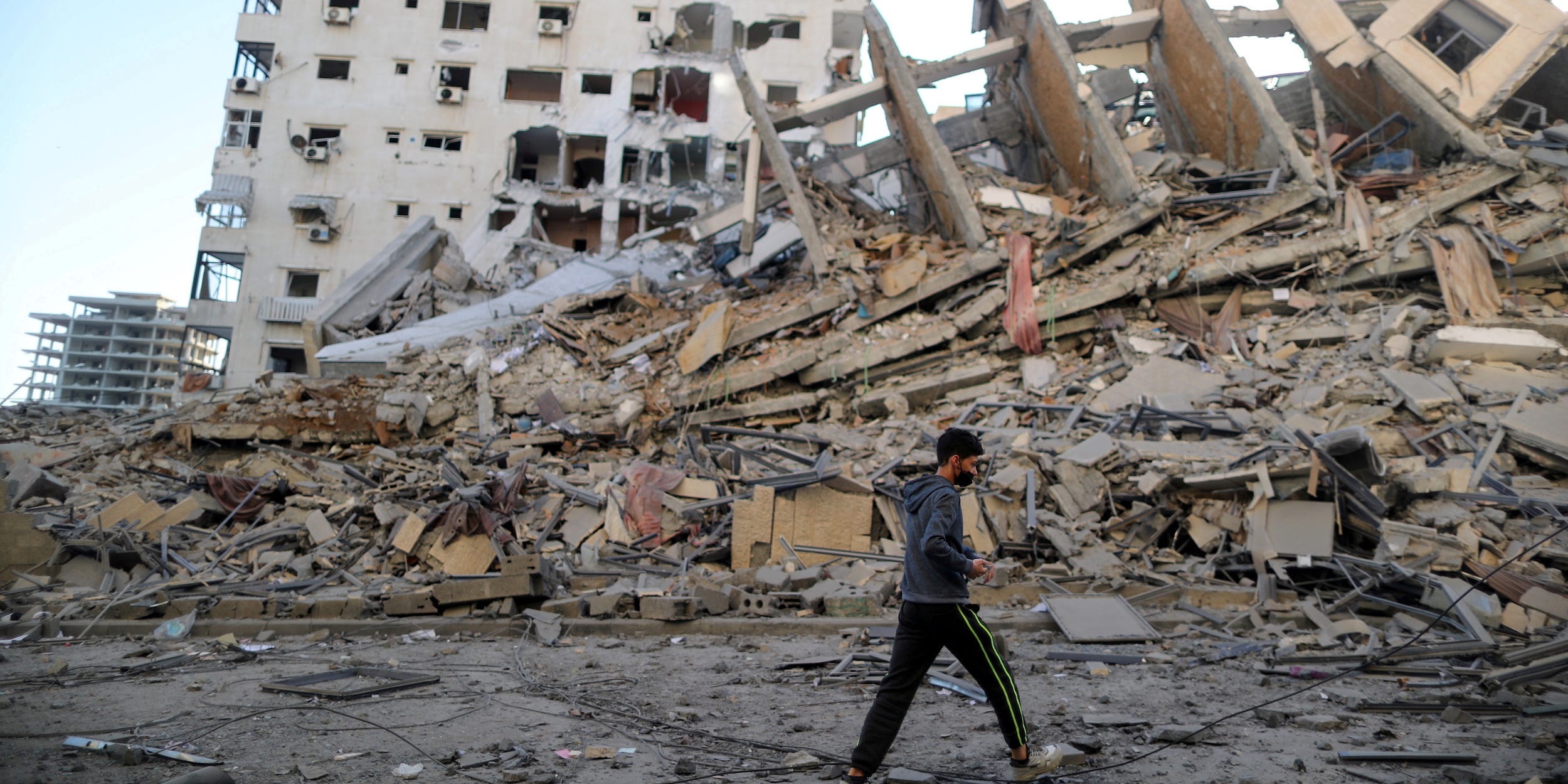 A Palestinian boy walks past the remains of a tower building which was destroyed in Israeli air strikes, amid a flare-up of Israeli-Palestinian violence, in Gaza City May 12, 2021.