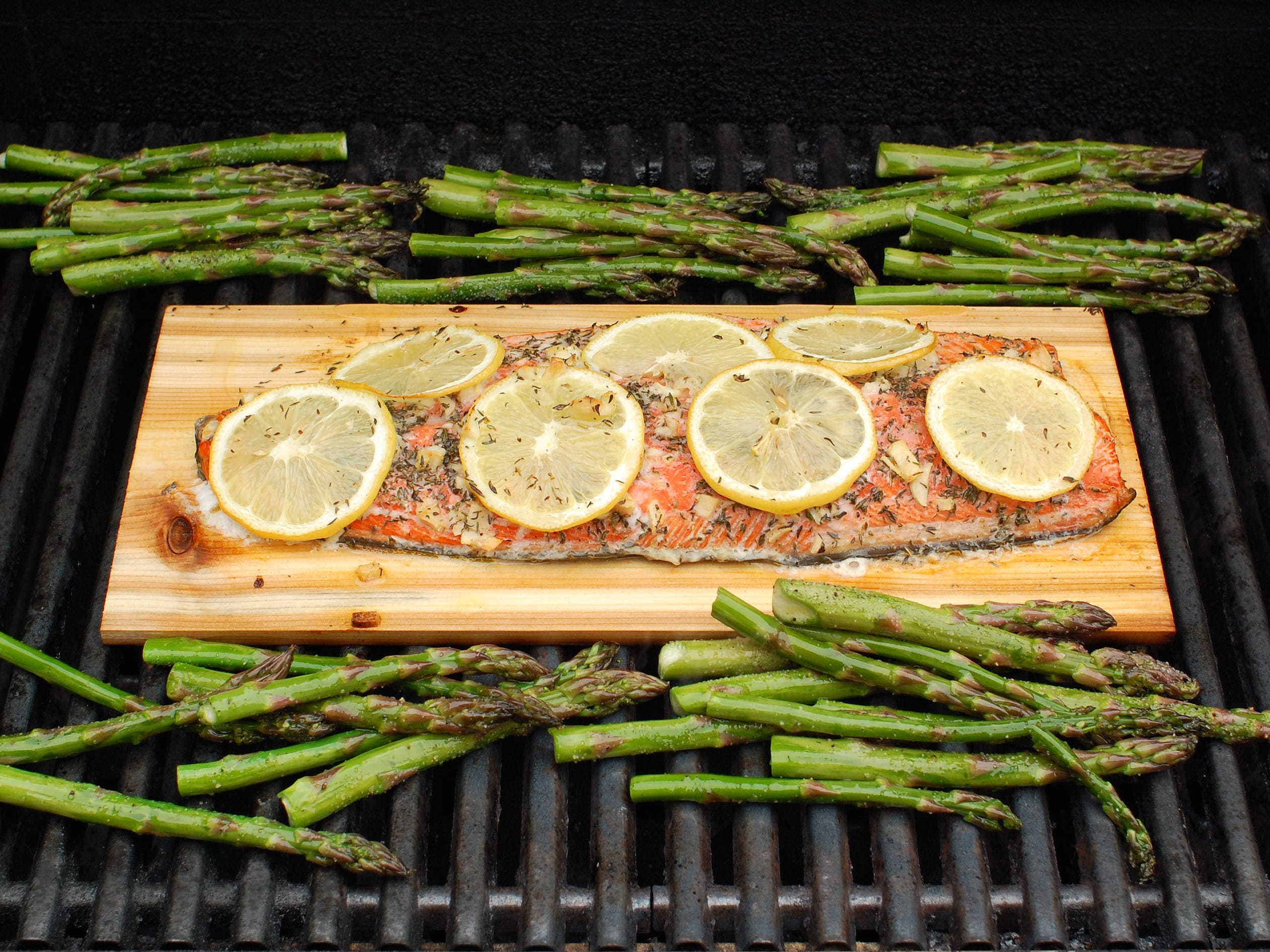 Cedar plank salmon on the grill alongside grilled asparagus