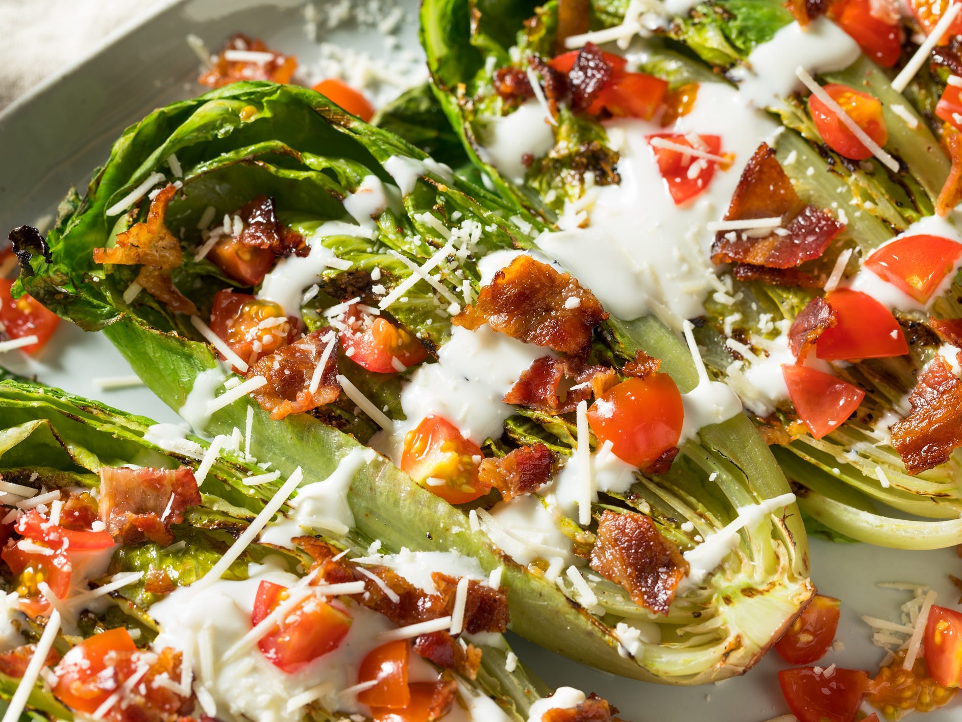 Grilled romaine lettuce topped with bacon, tomatoes, and blue cheese dressing