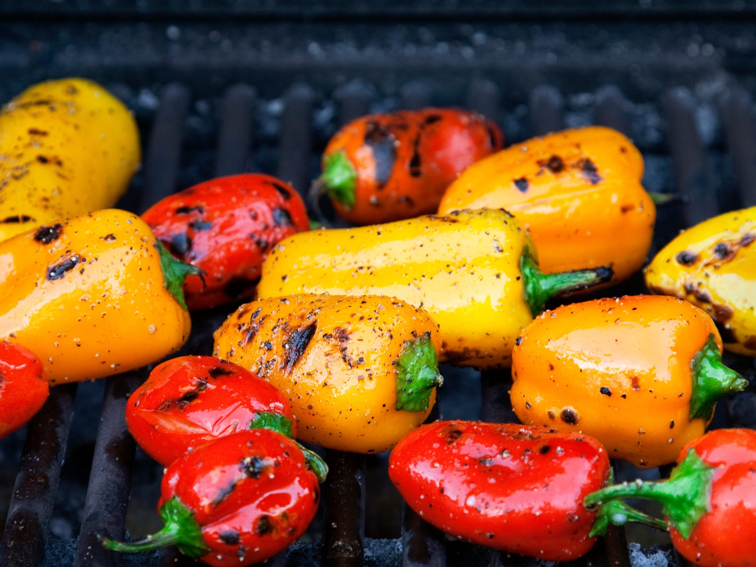 Small red and yellow peppers on a grill