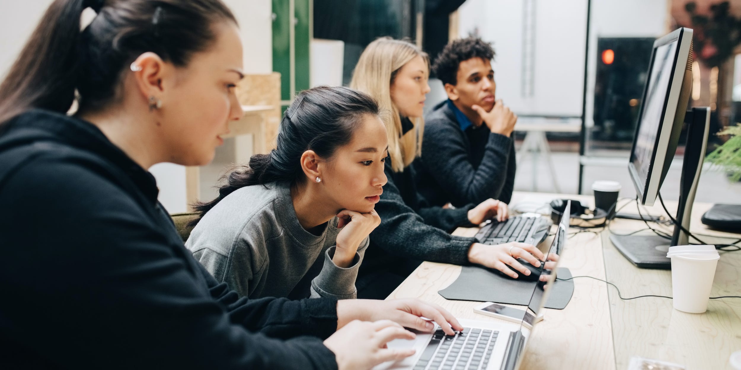 computer programmers sitting at desk looking at computers working together