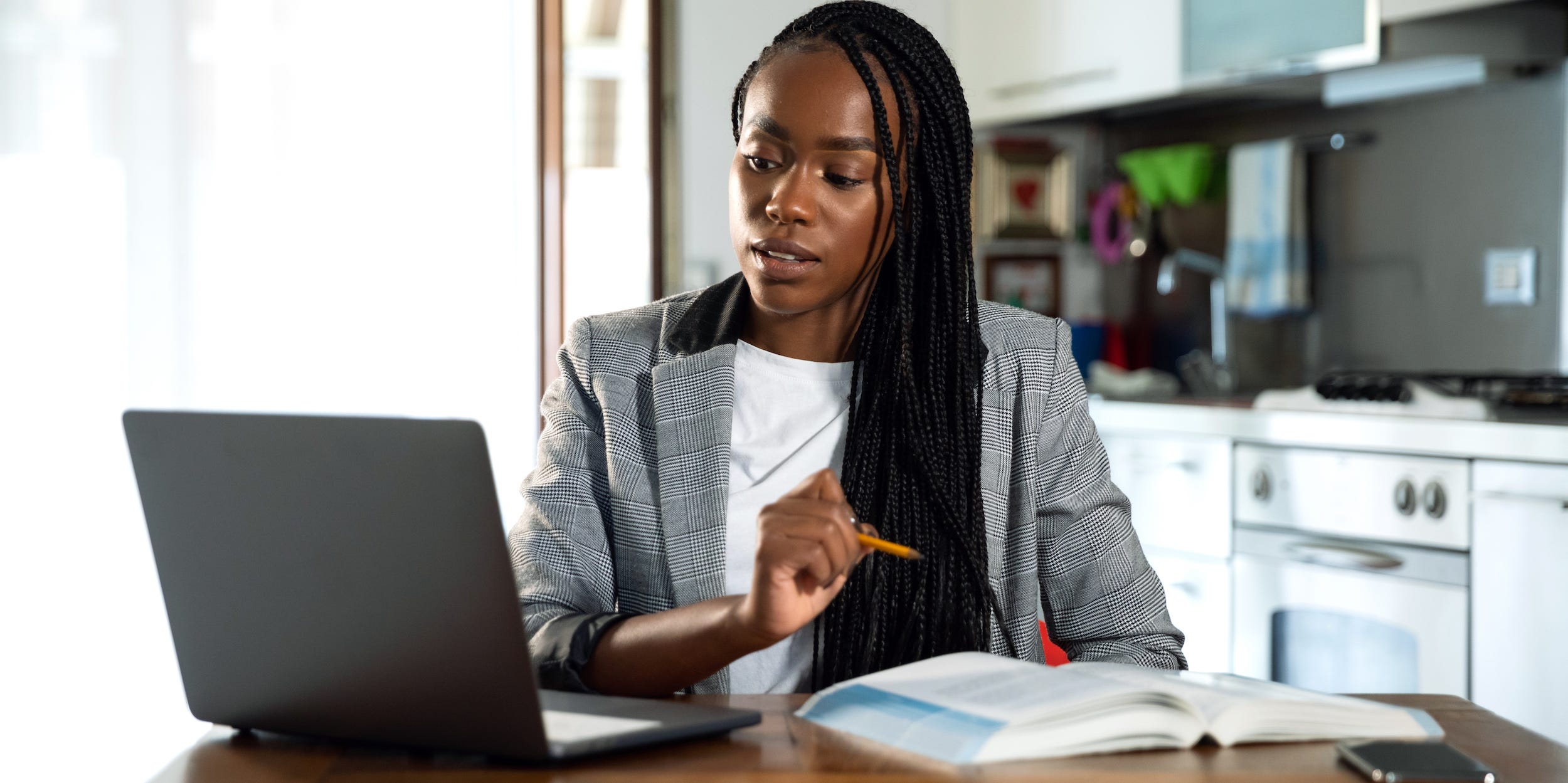 student or teacher using laptop and textbooks