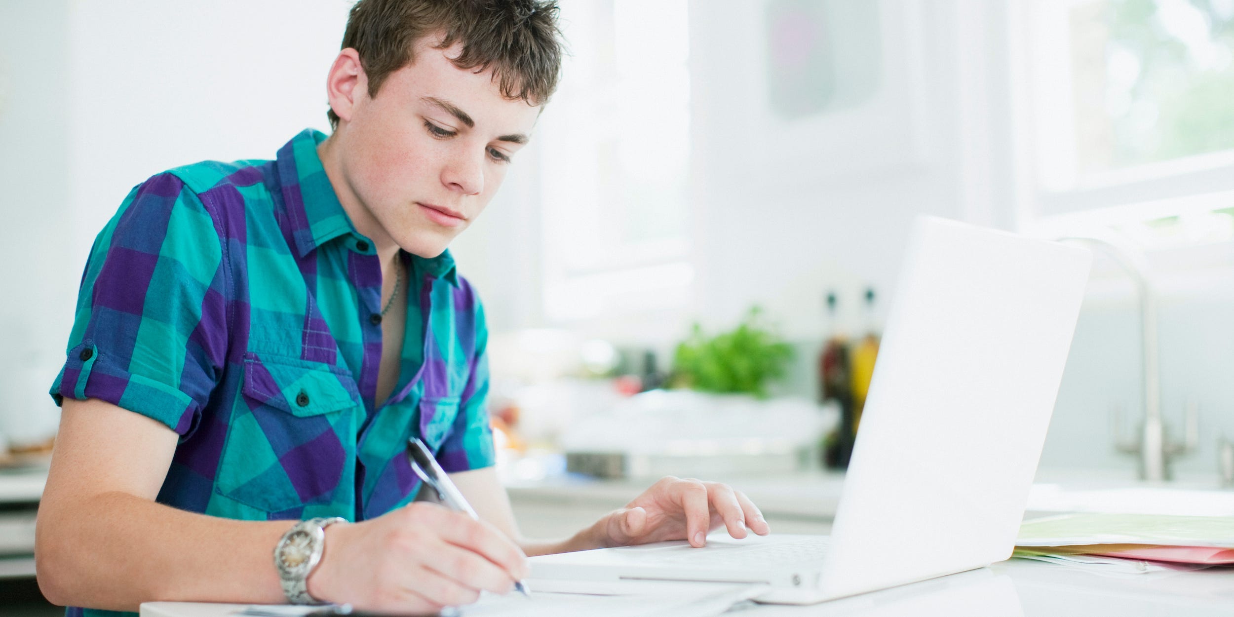 teen student using laptop and studying with textbooks