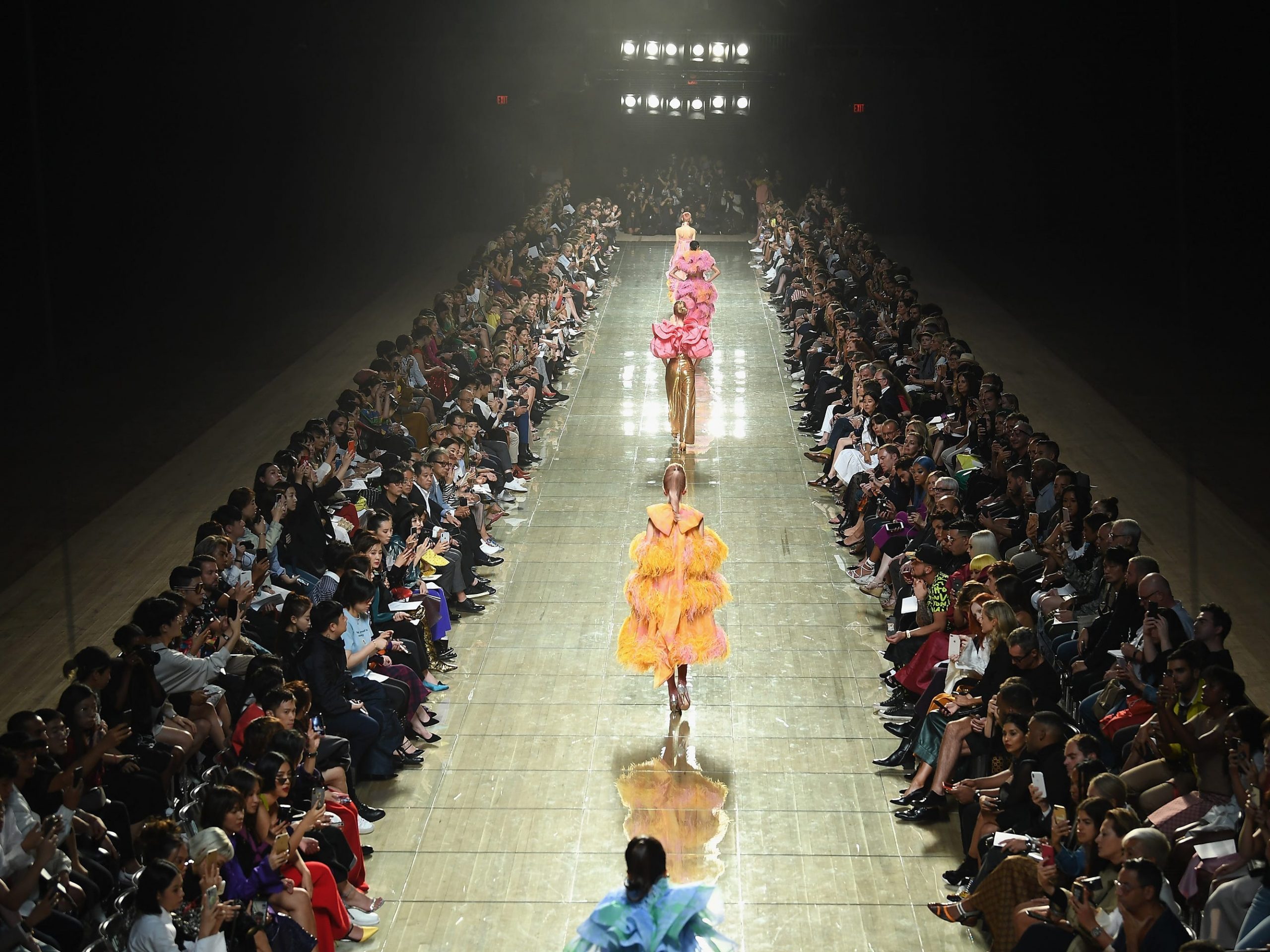 Models walk down a runway surrounded by spectators at a Marc Jacob fashion show.