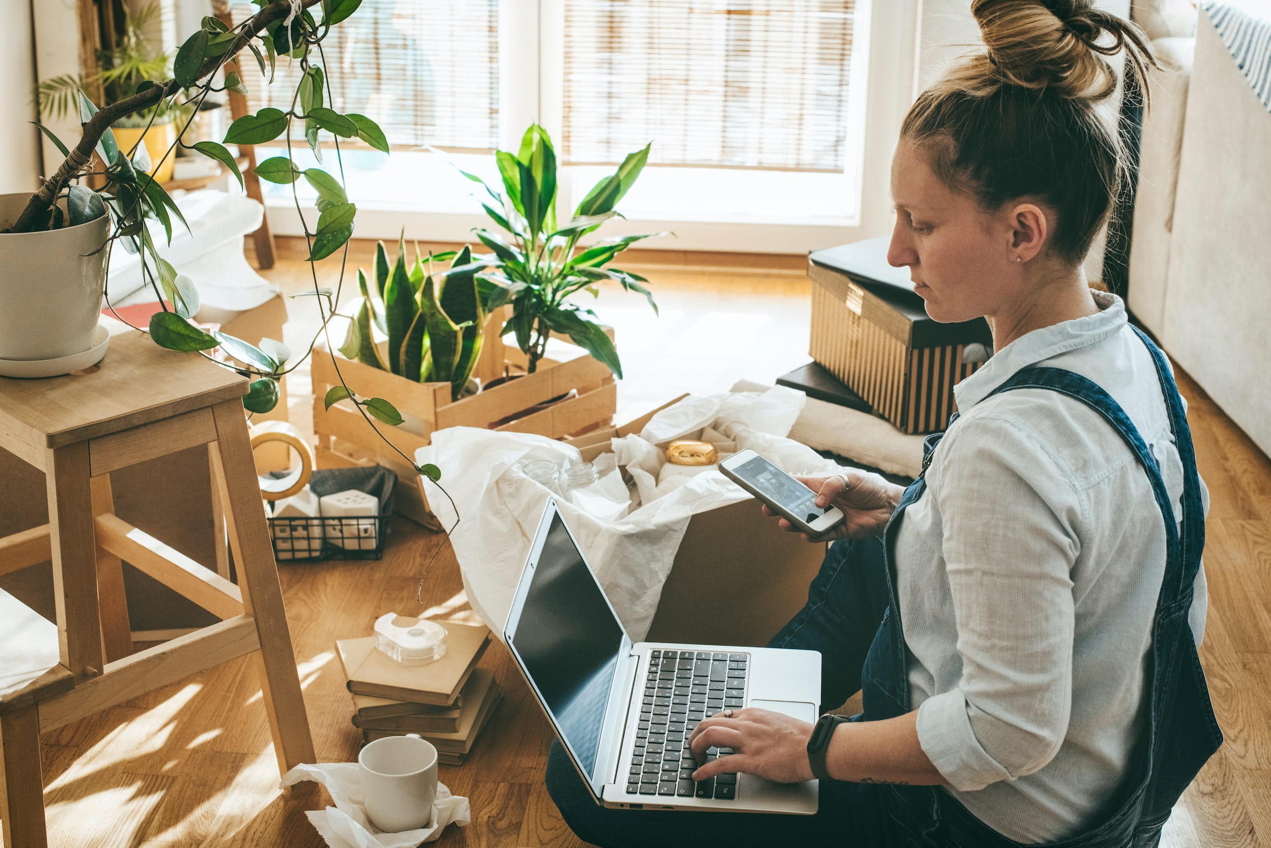 woman unpacking boxes with laptop and phone