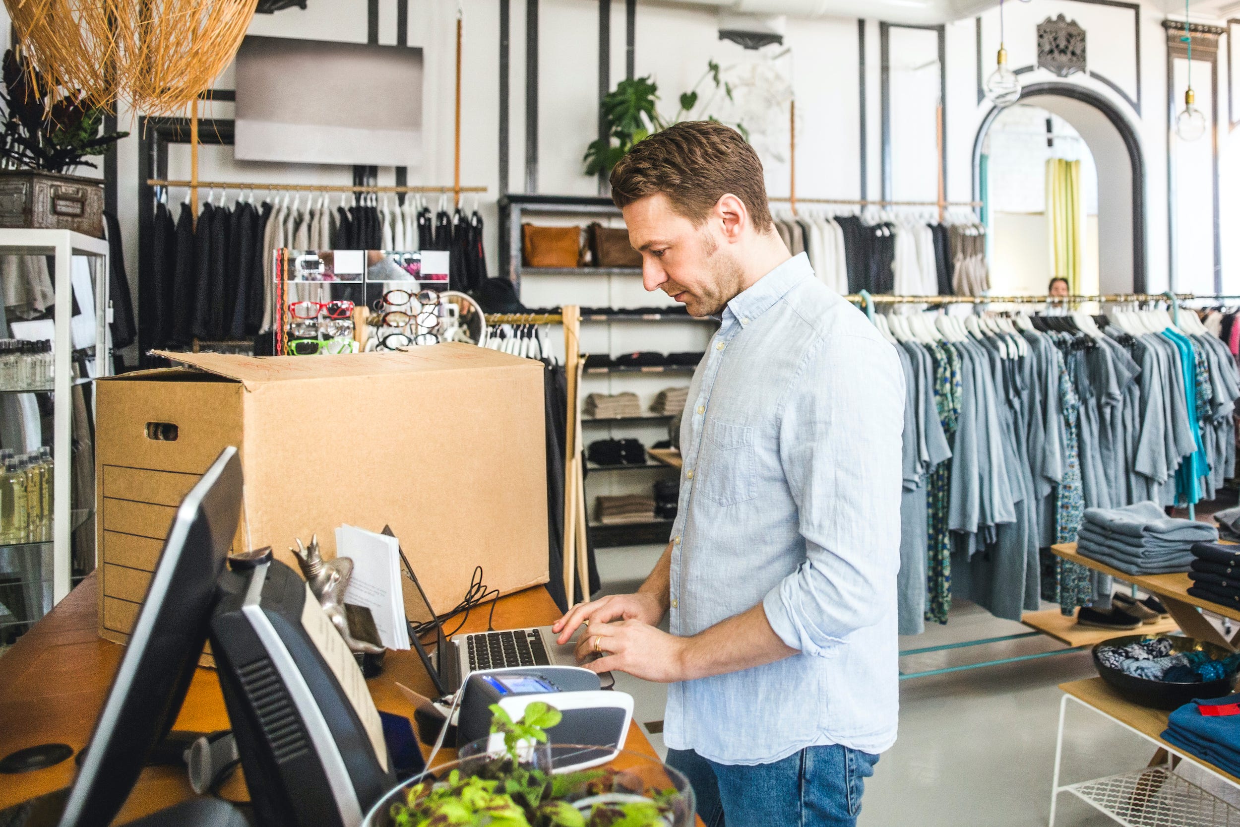 store owner shipping box using laptop in shop