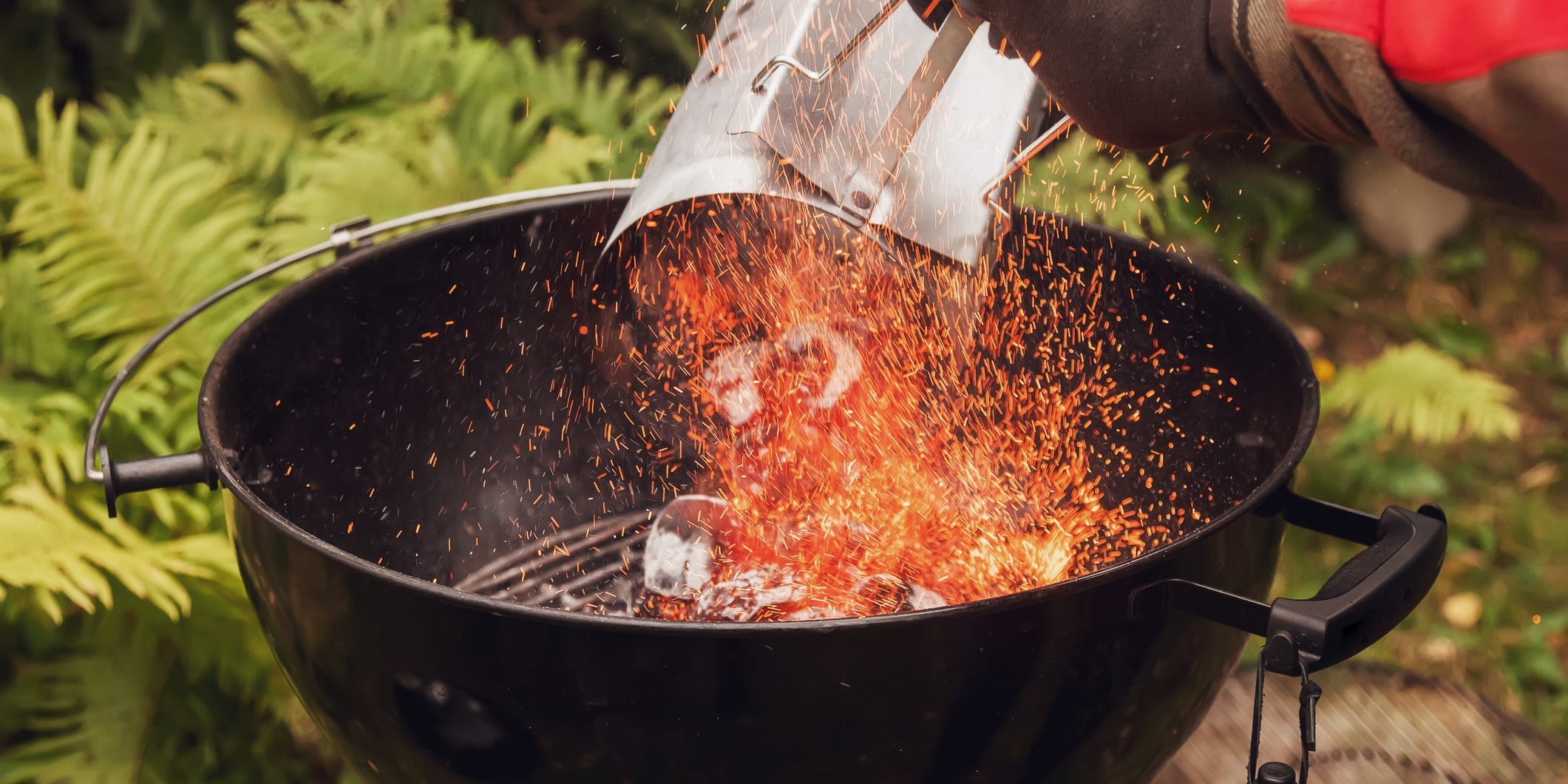 Pouring lit charcoal out of a chimney starter into a charcoal grill