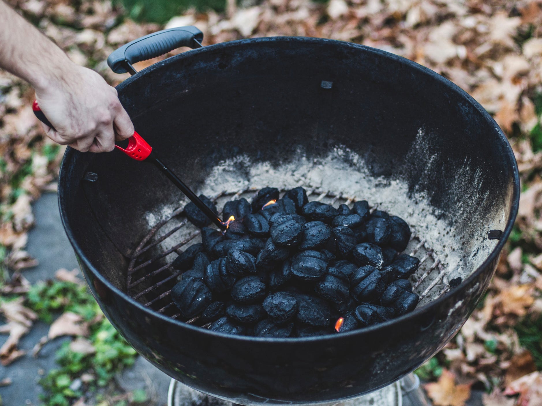 Hand-lighting charcoal inside a grill with a lighter