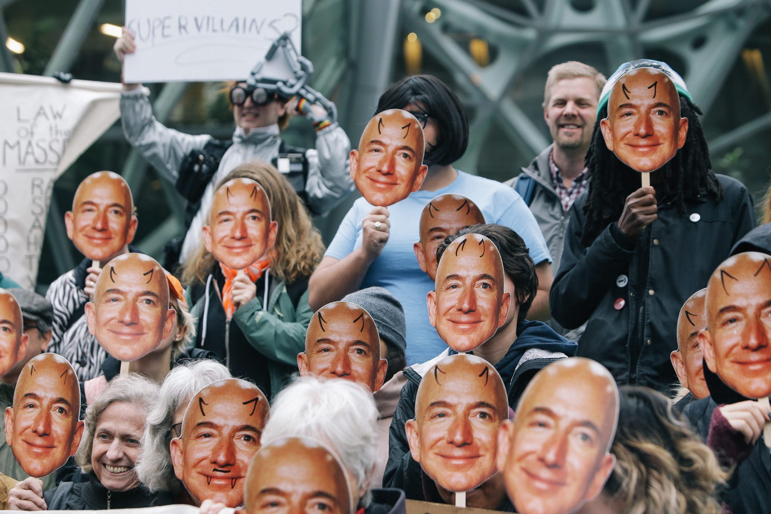 Several dozen protesters hold up Jeff Bezos masks as they gather downtown to denounce Amazon for providing their facial recognition software, ""Rekognition,"" to the Immigration and Customs Enforcement Agency (ICE) and, thereby, supporting the Trump Admin