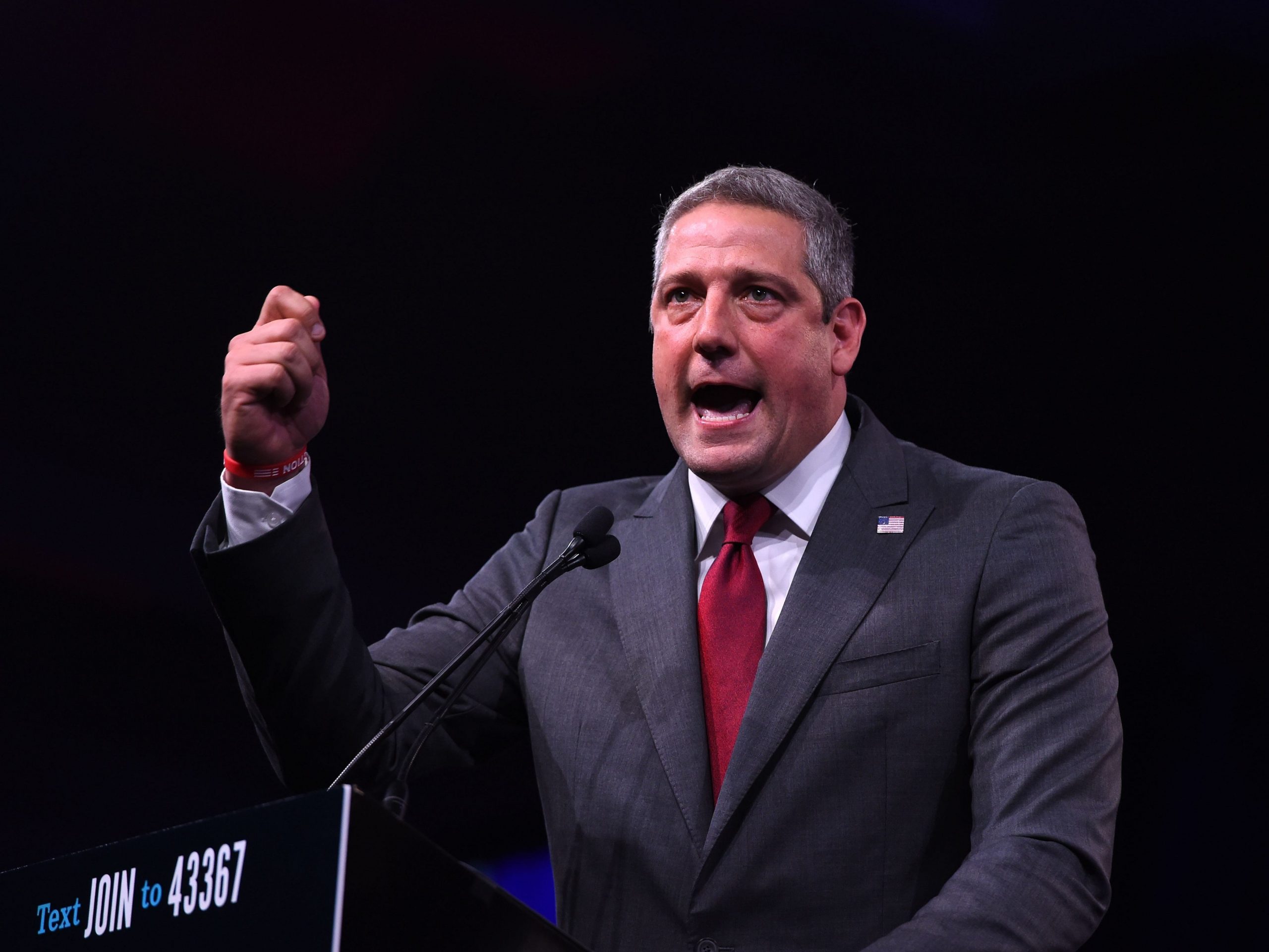 Tim Ryan wears a gray suit and red tie as he delivers an impassioned speech
