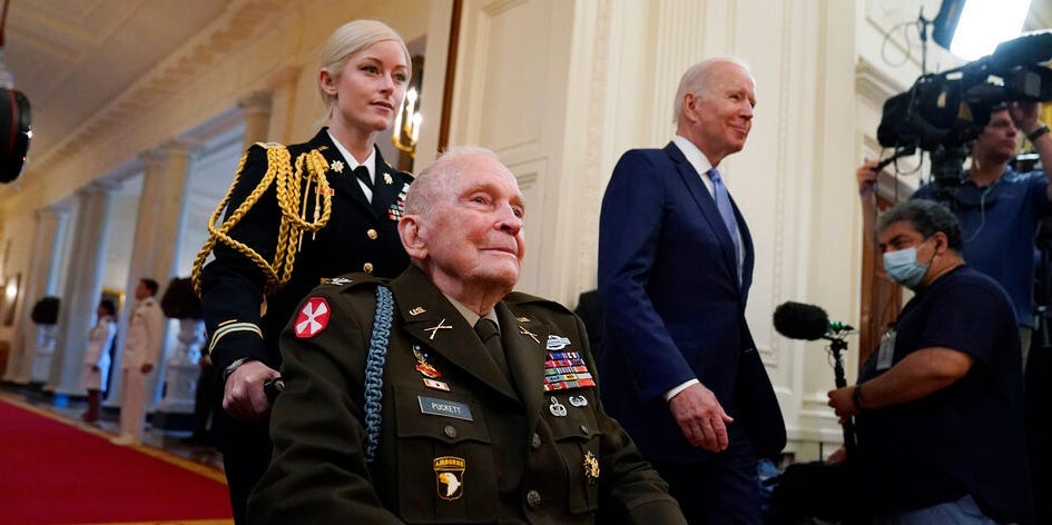 President Joe Biden arrives with retired U.S. Army Col. Ralph Puckett, who will be presented the Medal of Honor, in the East Room of the White House, Friday, May 21, 2021, in Washington