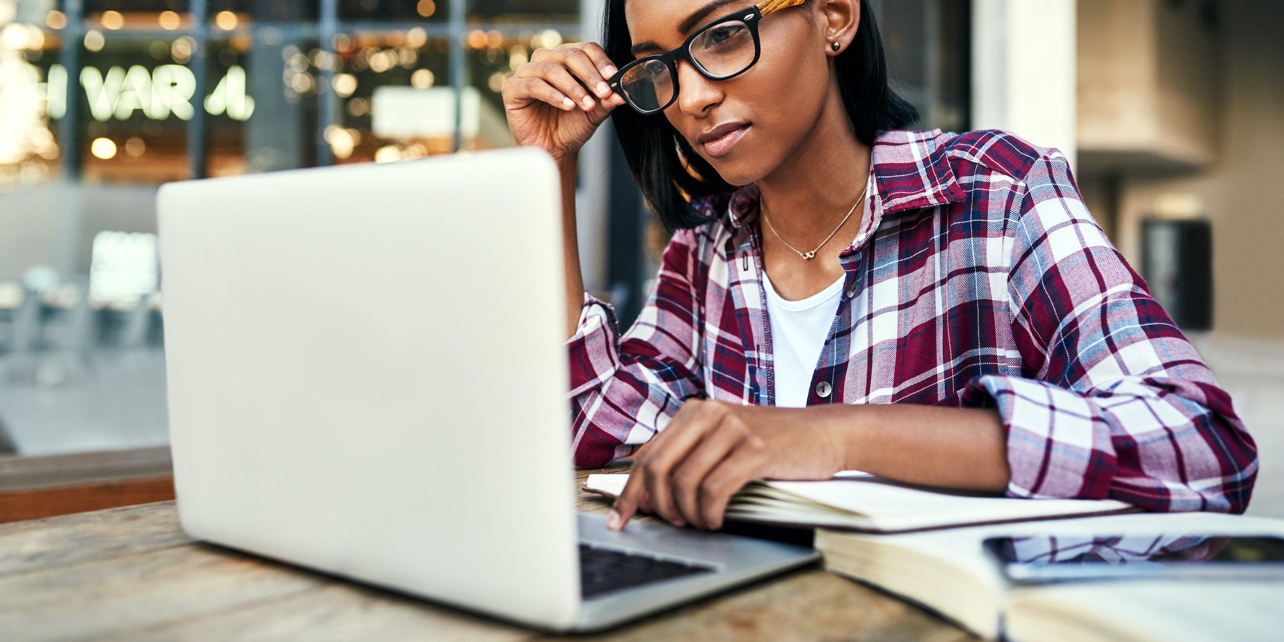 student working on laptop with textbooks