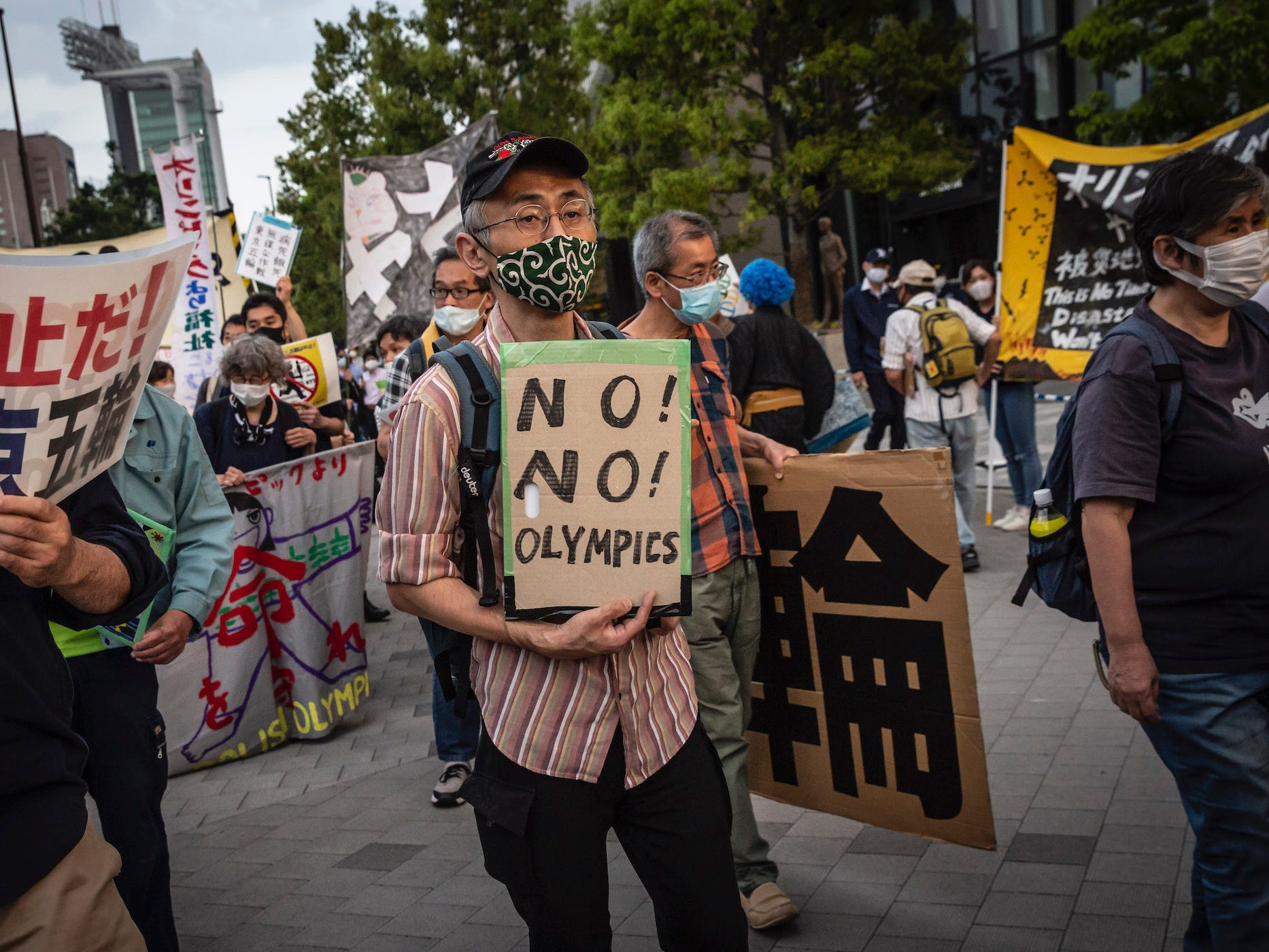 protesters hold signs at a demonstration against the tokyo olympics, may 9 2021