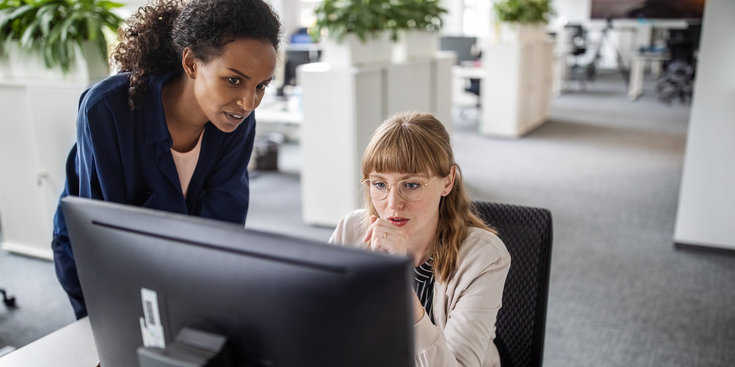 coworkers working at desktop computer together in office