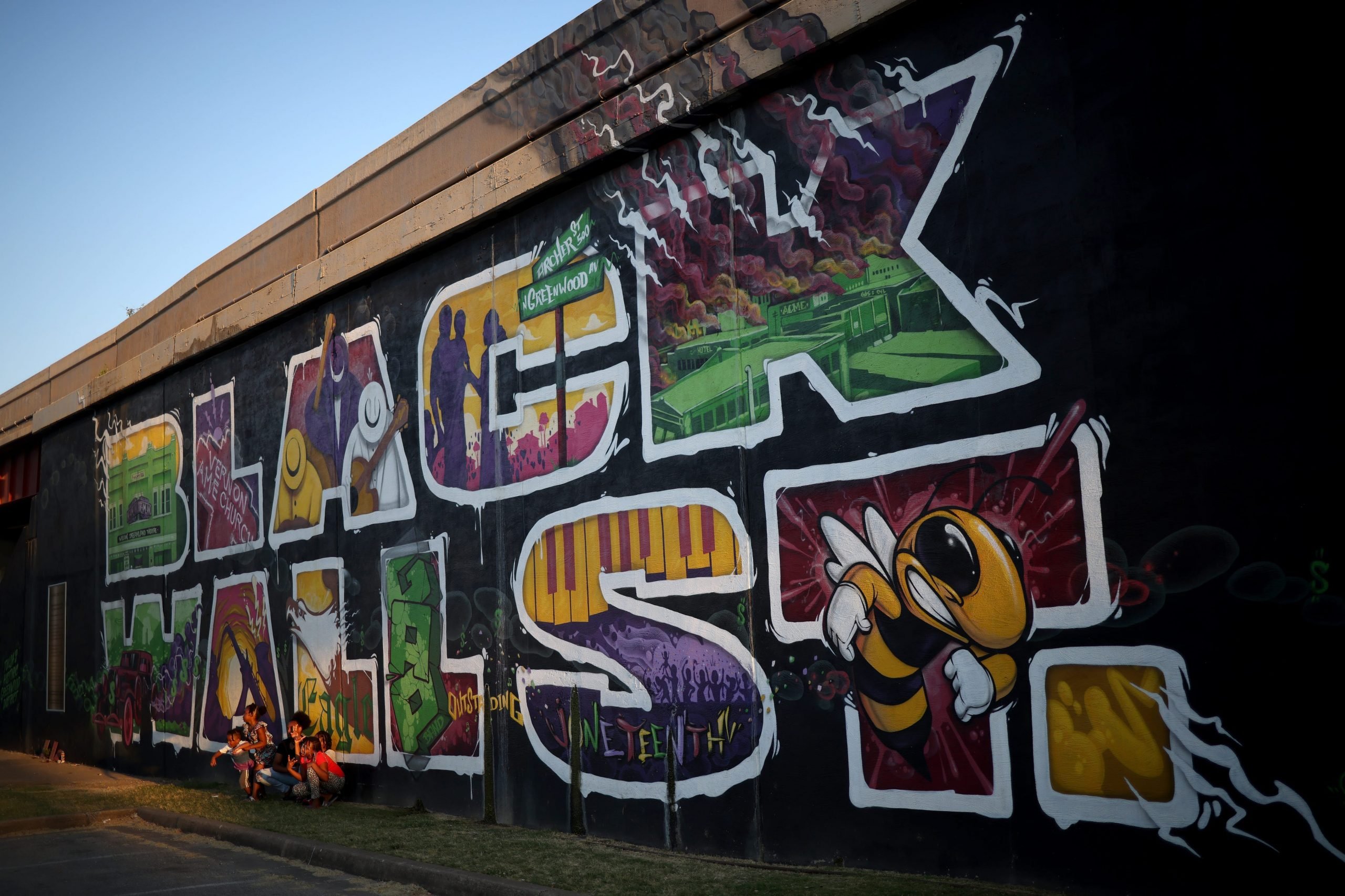 TULSA, OKLAHOMA - JUNE 18: Children pose for a photo in front of a mural marking Black Wall Street, also called the Greenwood Distric, June 18, 2020 in Tulsa, Oklahoma. The Black Wall Street Massacre happened in 1921 and was one of the worst race riots in the history of the United States where more than 35 square blocks of a predominantly black neighborhood were destroyed in two days of rioting leaving between 150-300 people dead.