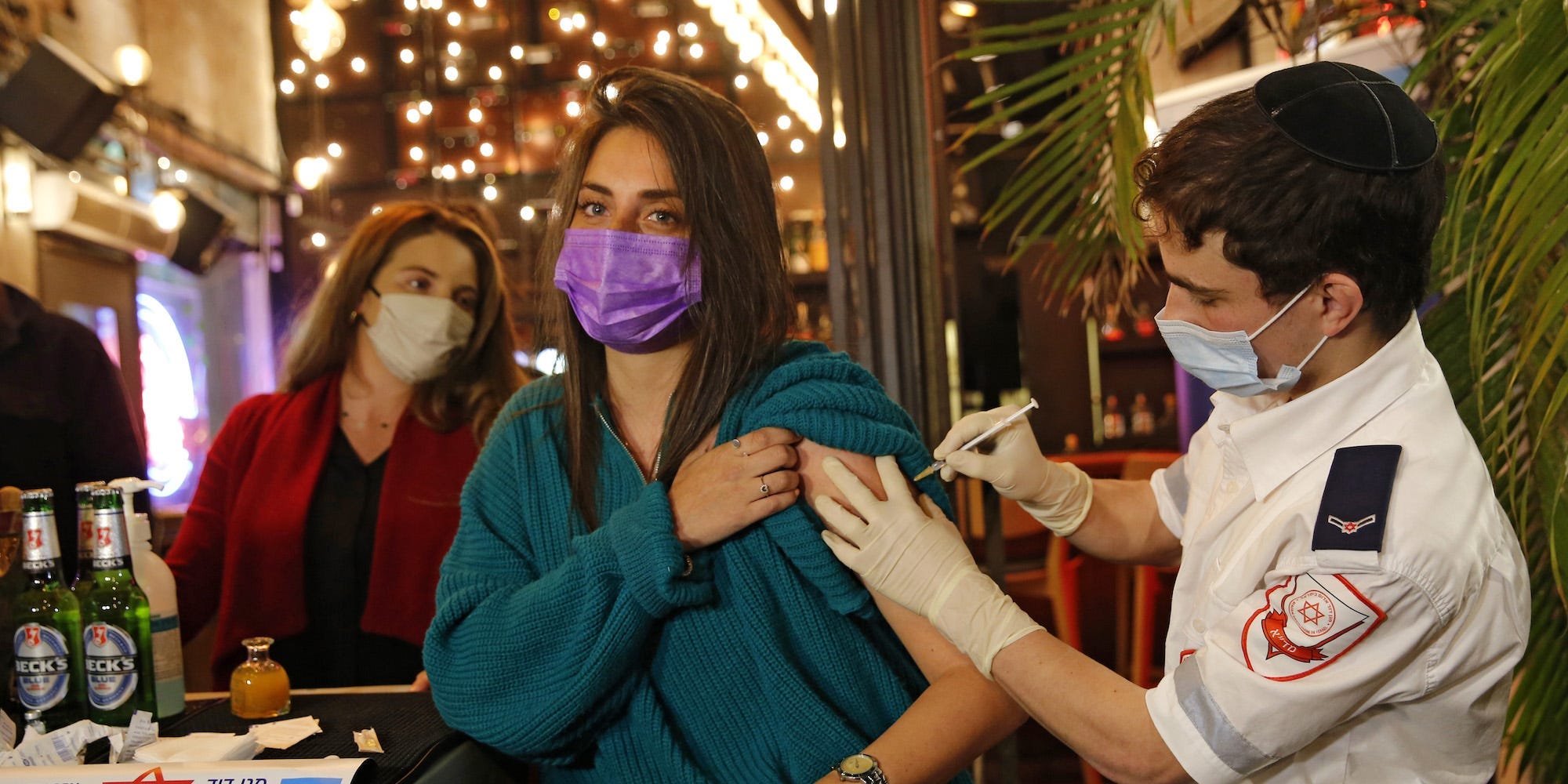 A health worker administers the COVID-19 vaccine to an Israeli at a bar in the coastal city of Tel Aviv on February 18, 2021. (Photo by GIL COHEN-MAGEN / AFP) (Photo by GIL COHEN-MAGEN/AFP via Getty Images)