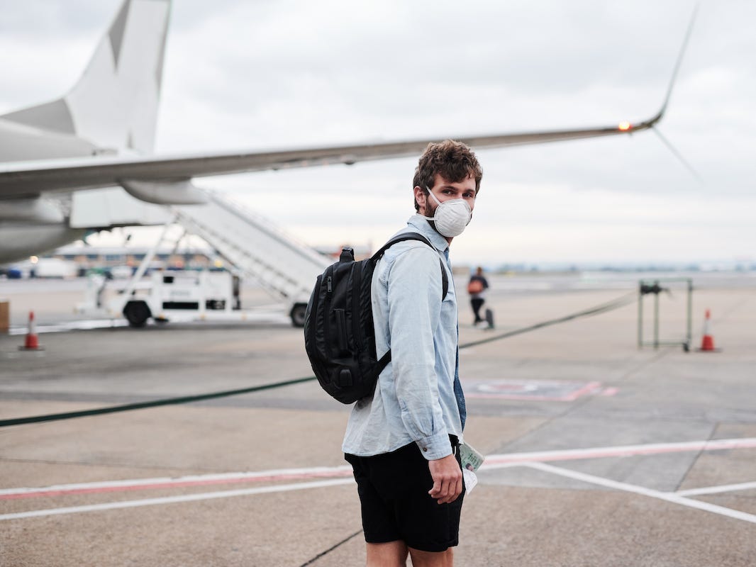 A person wearing a mask boards a plane.