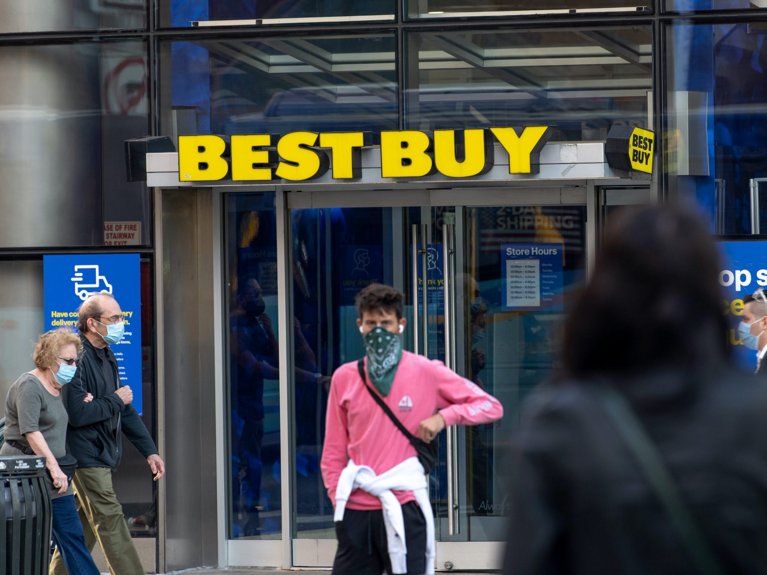 a person dressed in pink stands in front of a Best Buy store