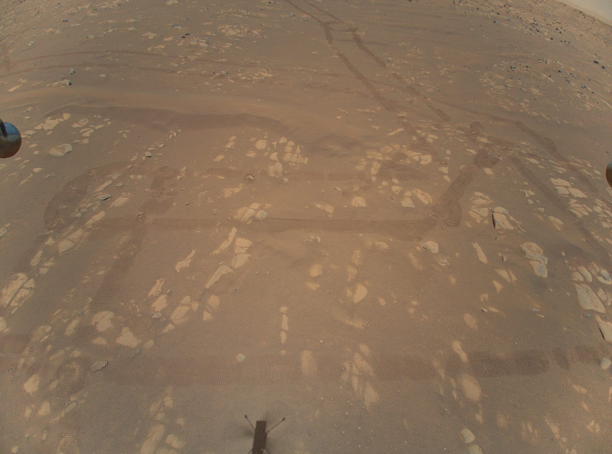 ingenuity shadow approaches perseverance rover wheel tracks in mars red dust