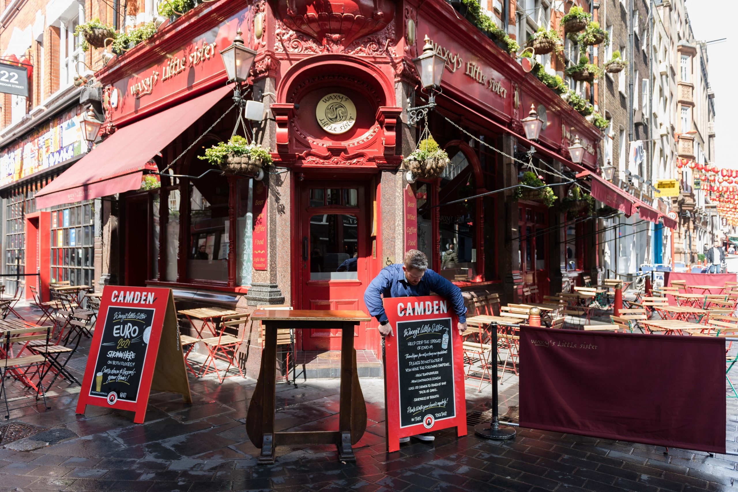 A staff member puts signs outside a pub in central London in May 2021