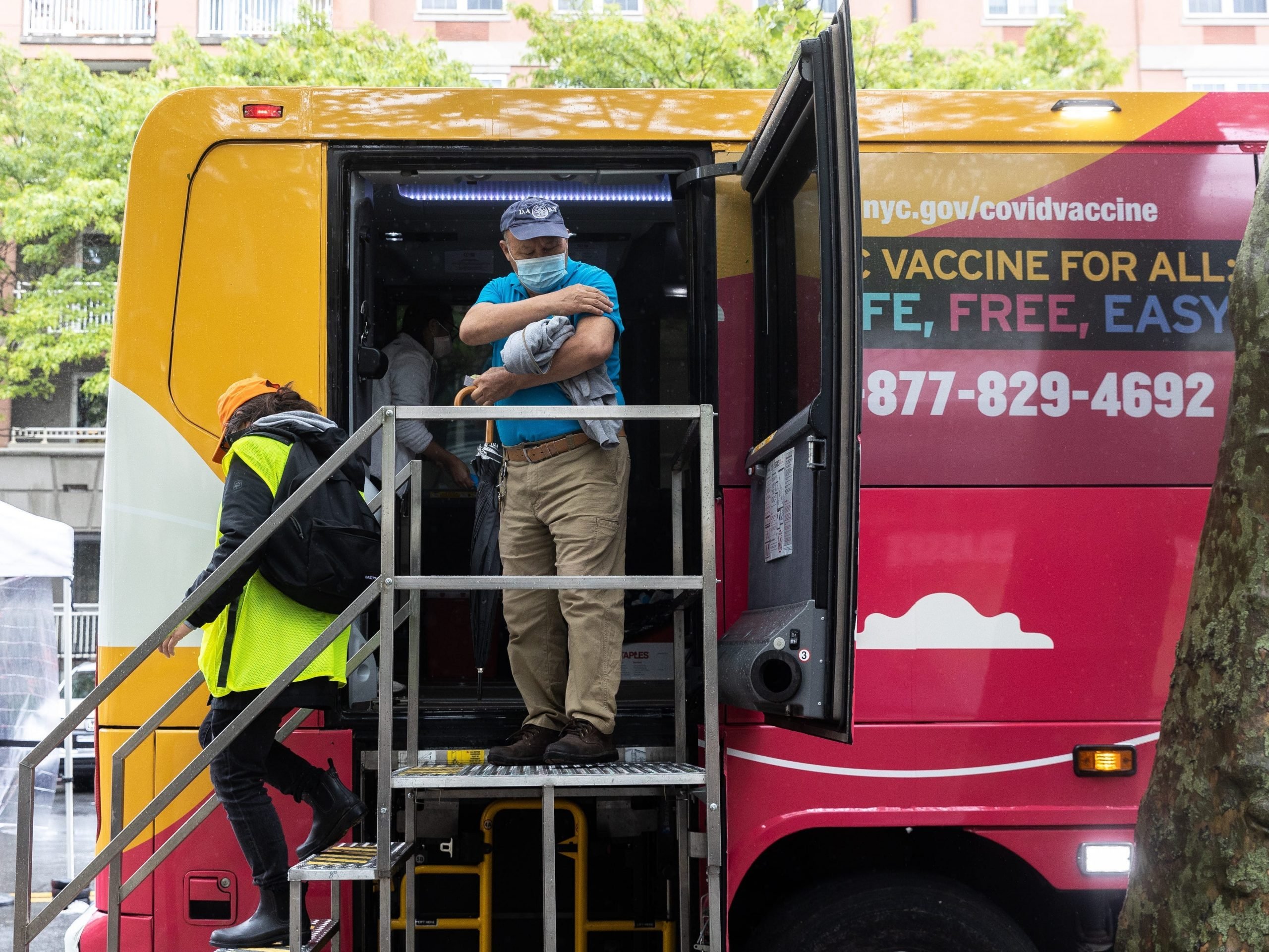 Man with mask on comes out of colourful van after coronavirus vaccination.