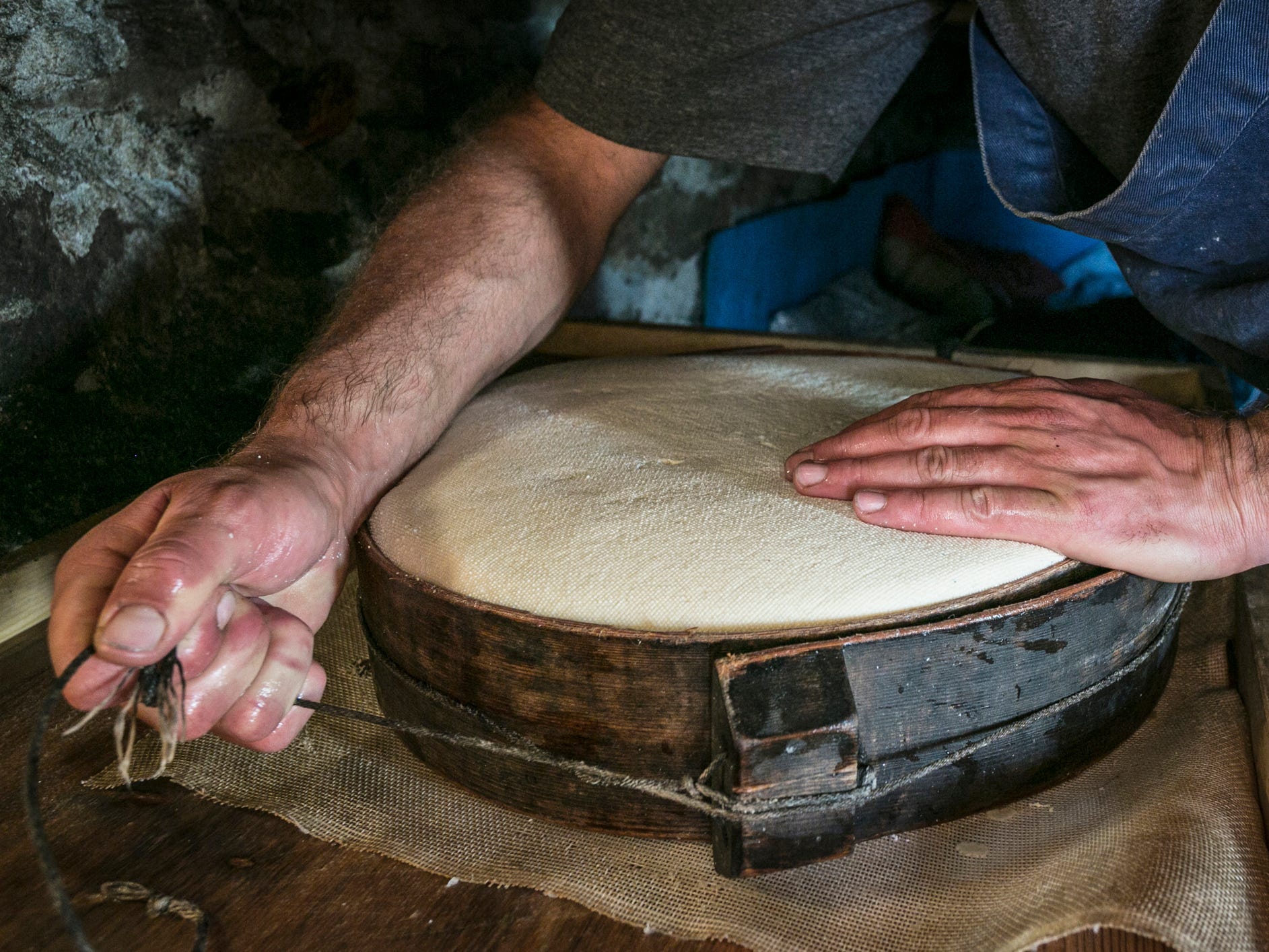 A man making a wheel of cheese