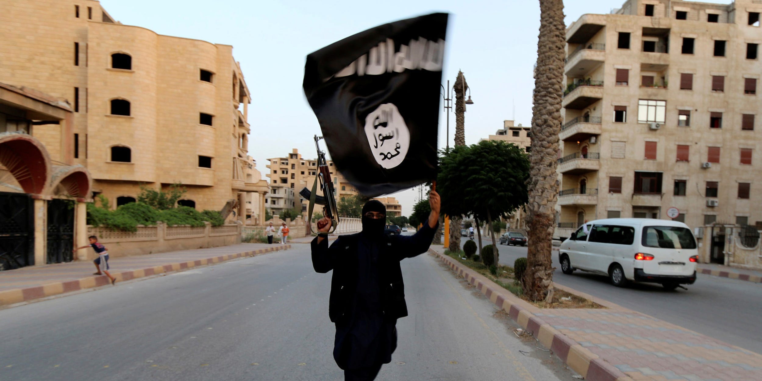 A member loyal to the Islamic State in Iraq and the Levant (ISIL) waves an ISIL flag in Raqqa, Syria June 29, 2014.