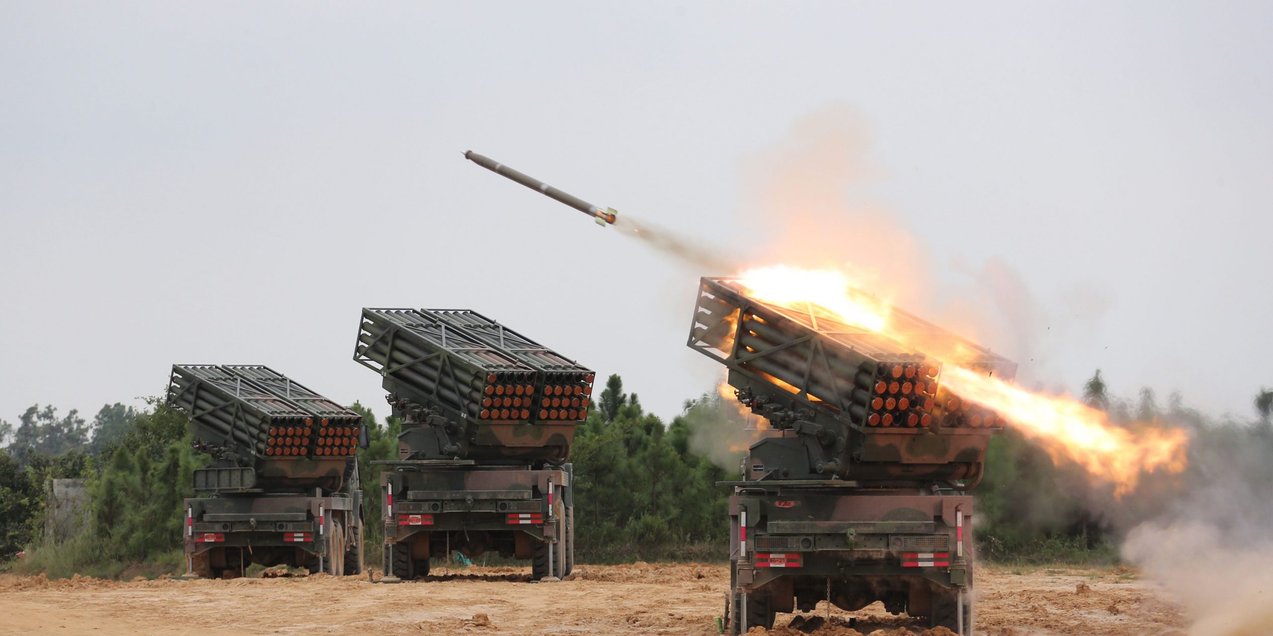 Vehicle-mounted multiple rocket launcher systems attached to an artillery detachment of a brigade under the PLA 72nd Group Army fire rockets at mock targets during a tactical live-fire training exercise