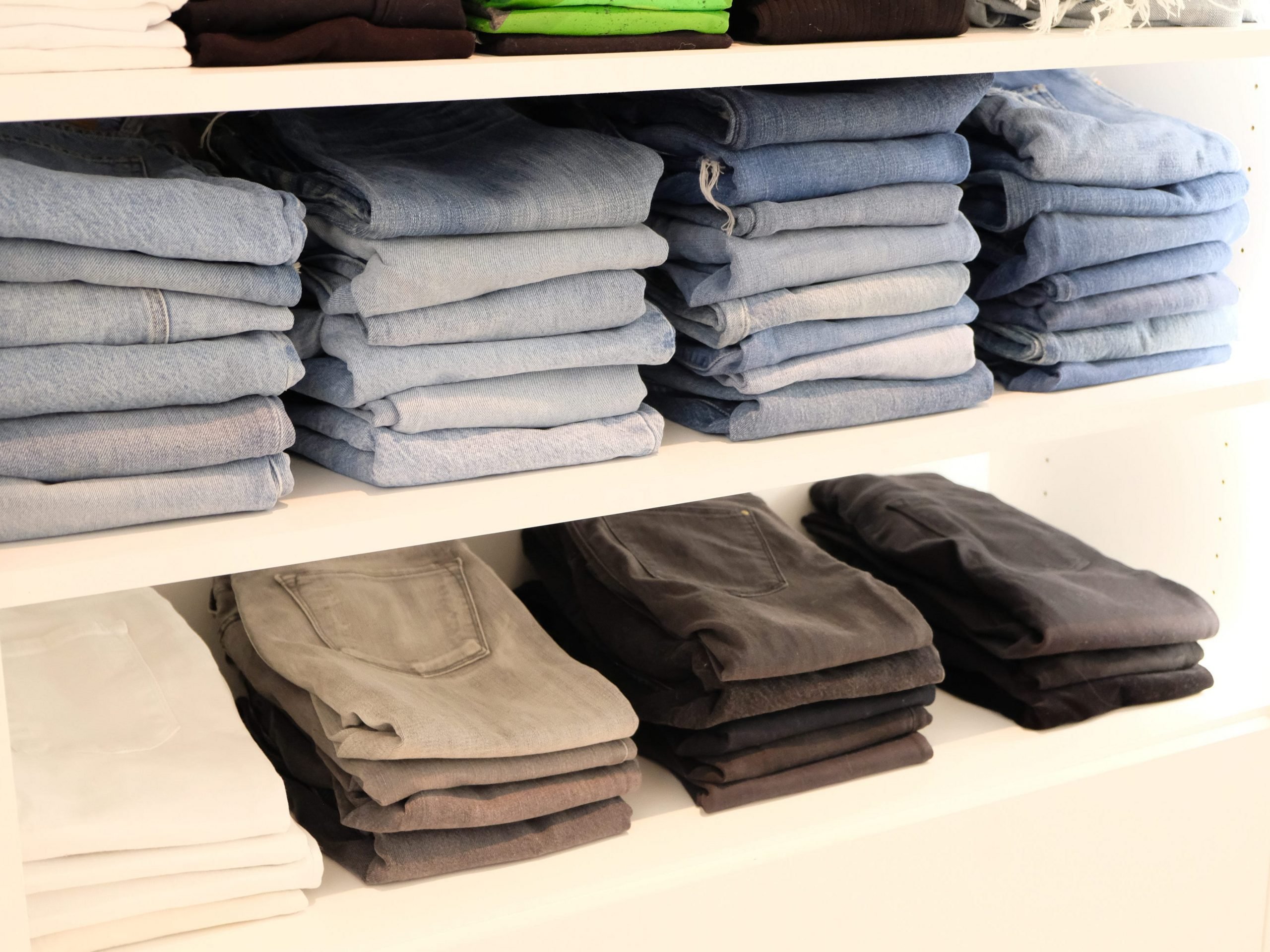Jeans and pants folded and stacked on closet shelves