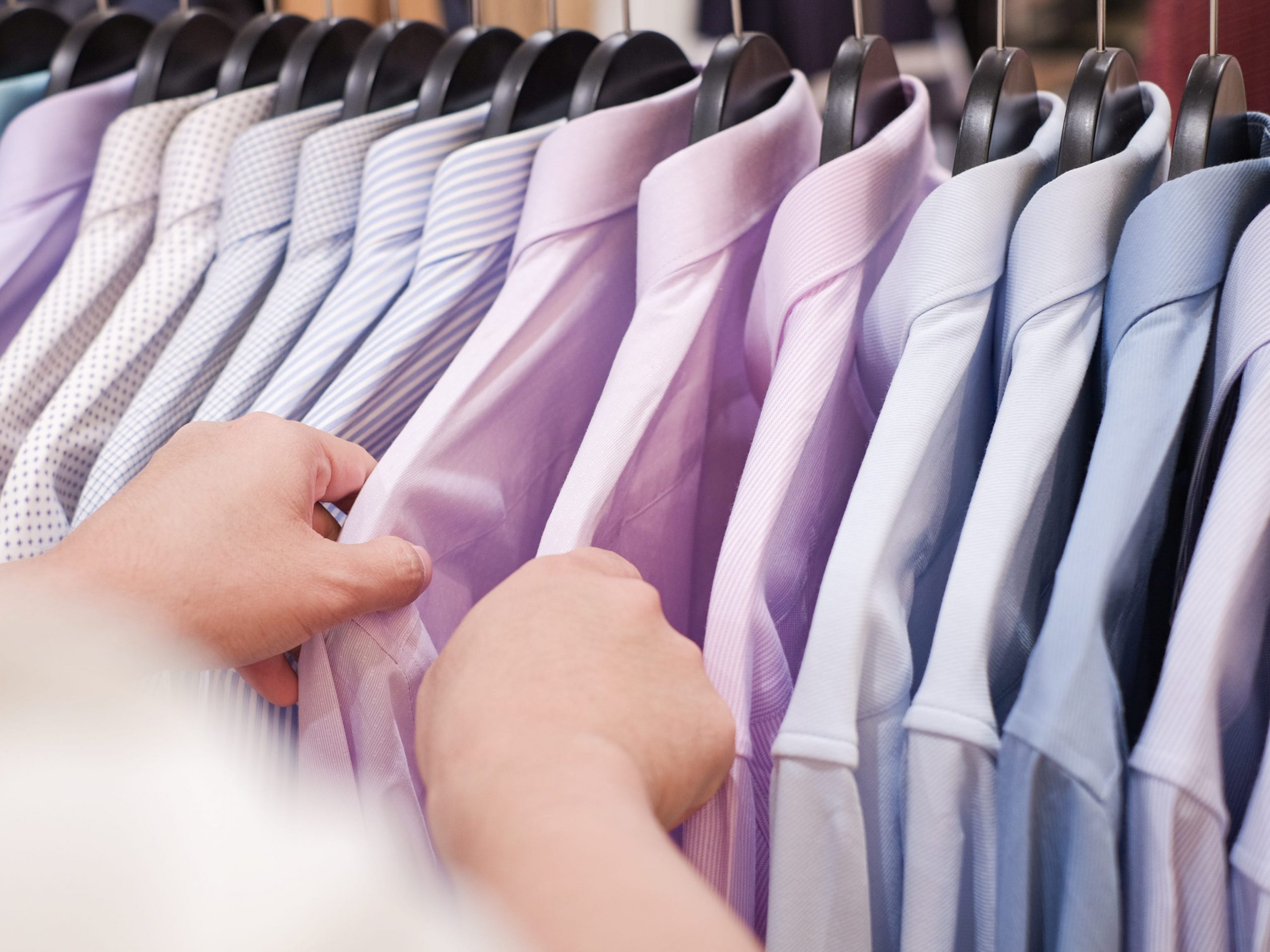 Hands sorting through men's dress shirts