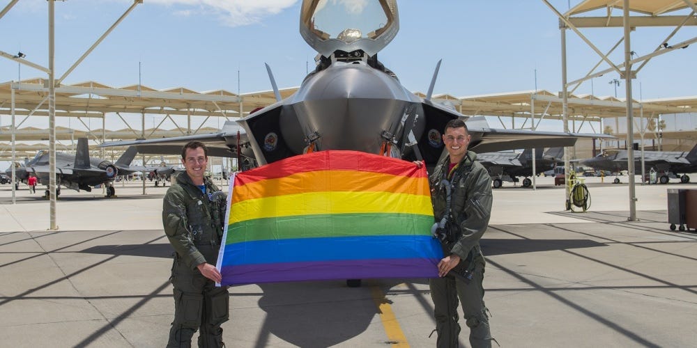 Maj. Tyler McBride, 62nd Fighter Squadron F-35A Lightning II instructor pilot, and Capt. Justin Lennon, 56th Training Squadron F-35 instructor pilot, hold an LGBTQ+ Pride flag after a Pride Month flyby June 26, 2020, at Luke Air Force Base, Ariz