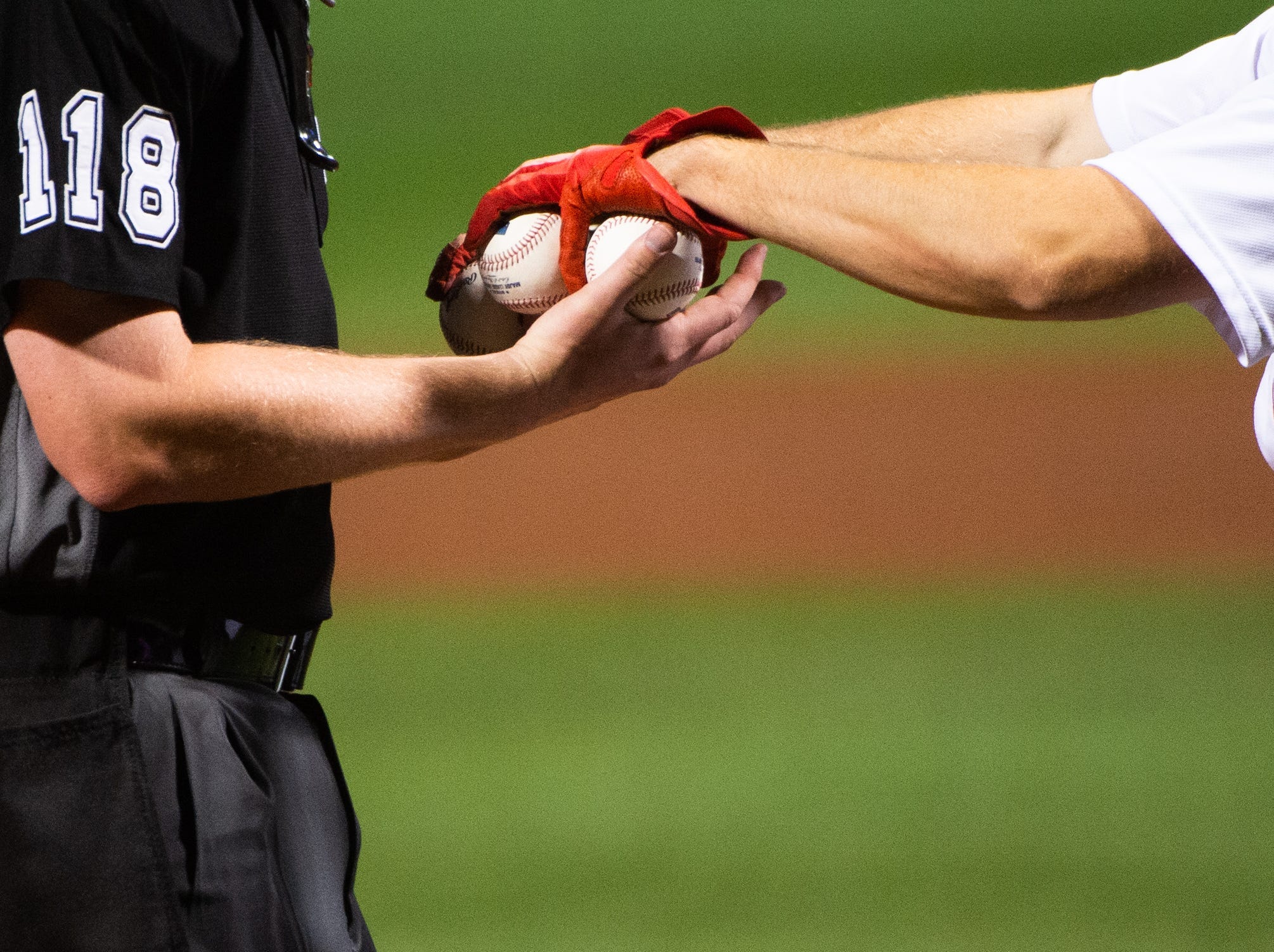 An MLB umpire is handed baseballs