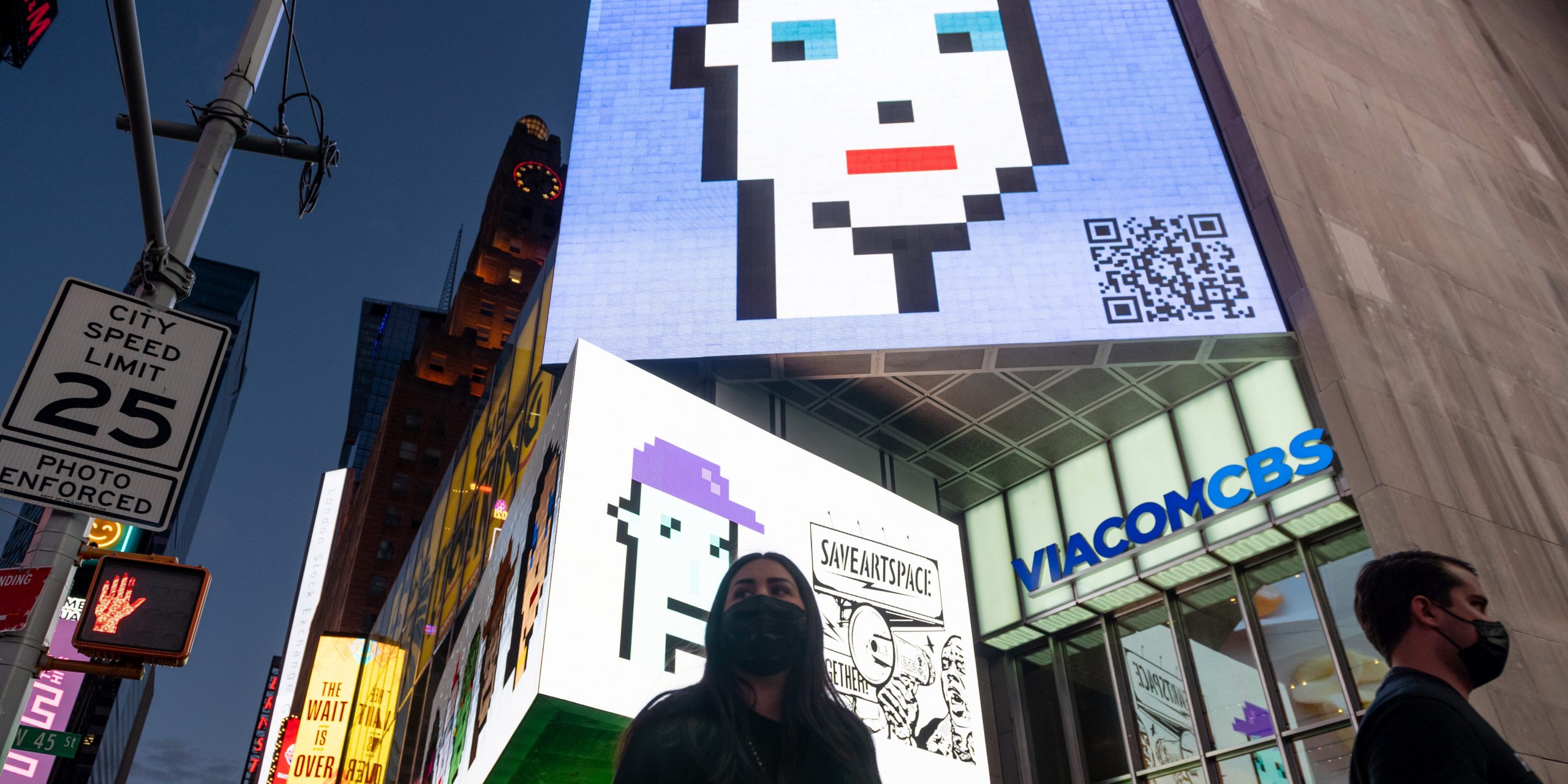 People walk past a CryptoPunk digital art NFT displayed on a digital billboard in Times Square.