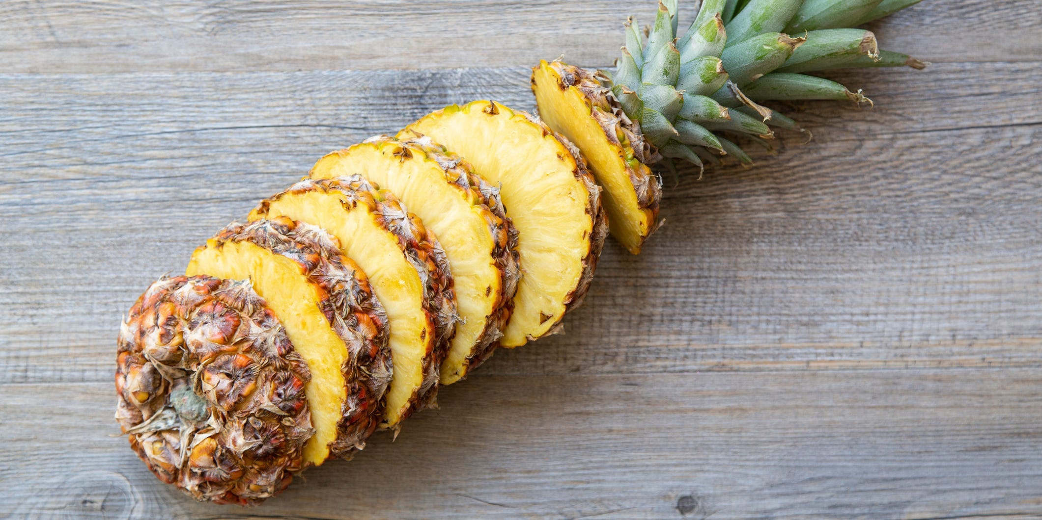 A pineapple cut into segments laid out on a wood table