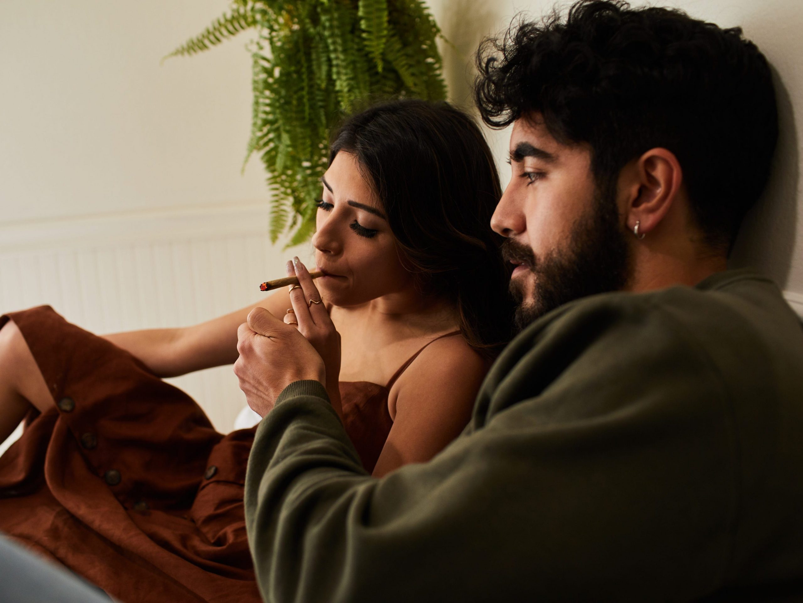 A couple smokes a joint together in bed.