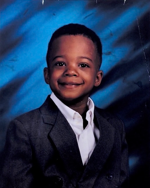 a young boy smiles for what looks to be a school photo